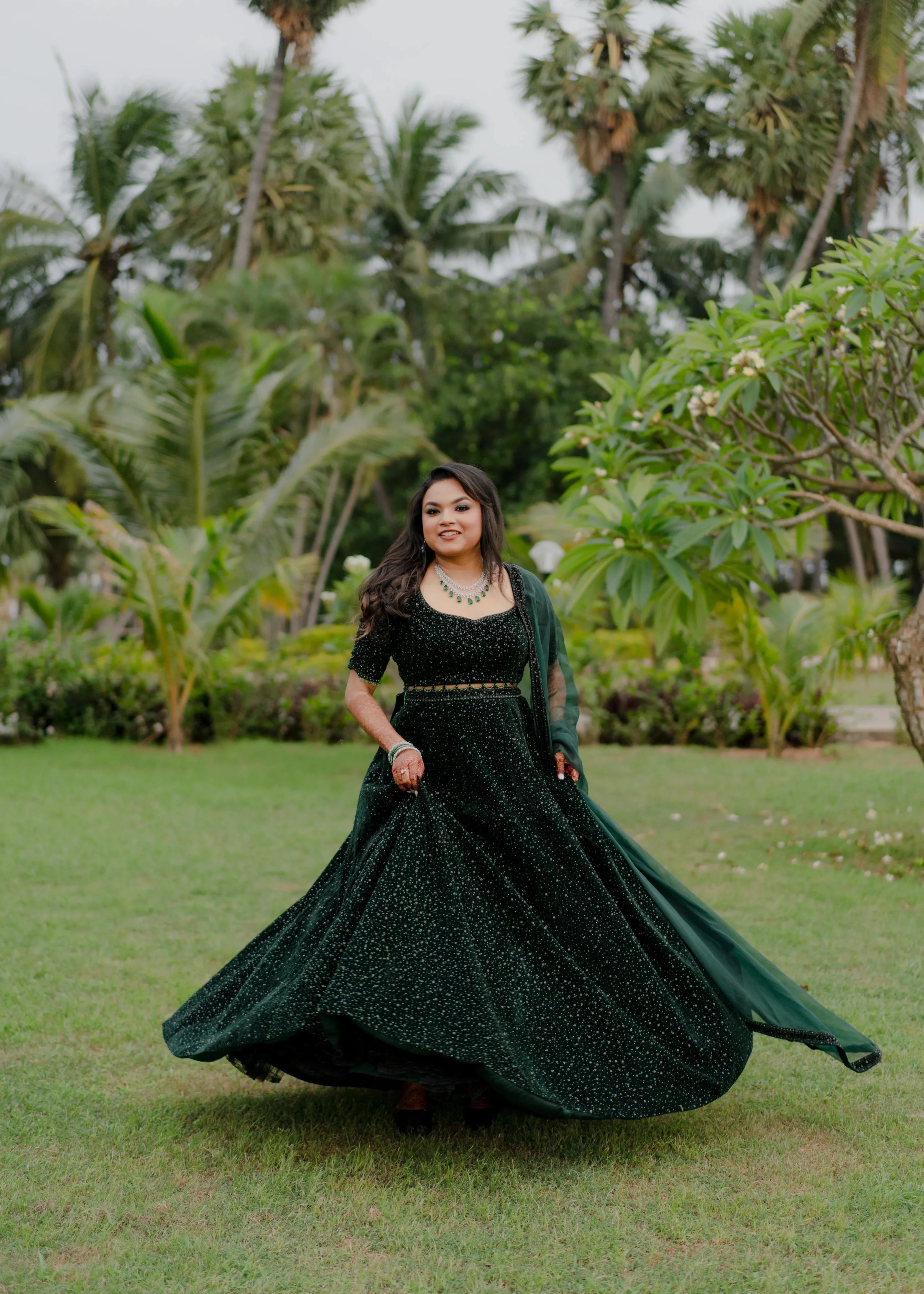 Bride Haripriya from USA twirling on the lawn in a bottle green velvet lehenga, intricately handcrafted with sequins, cutdana, beads and crystals by team Archana Karthick.