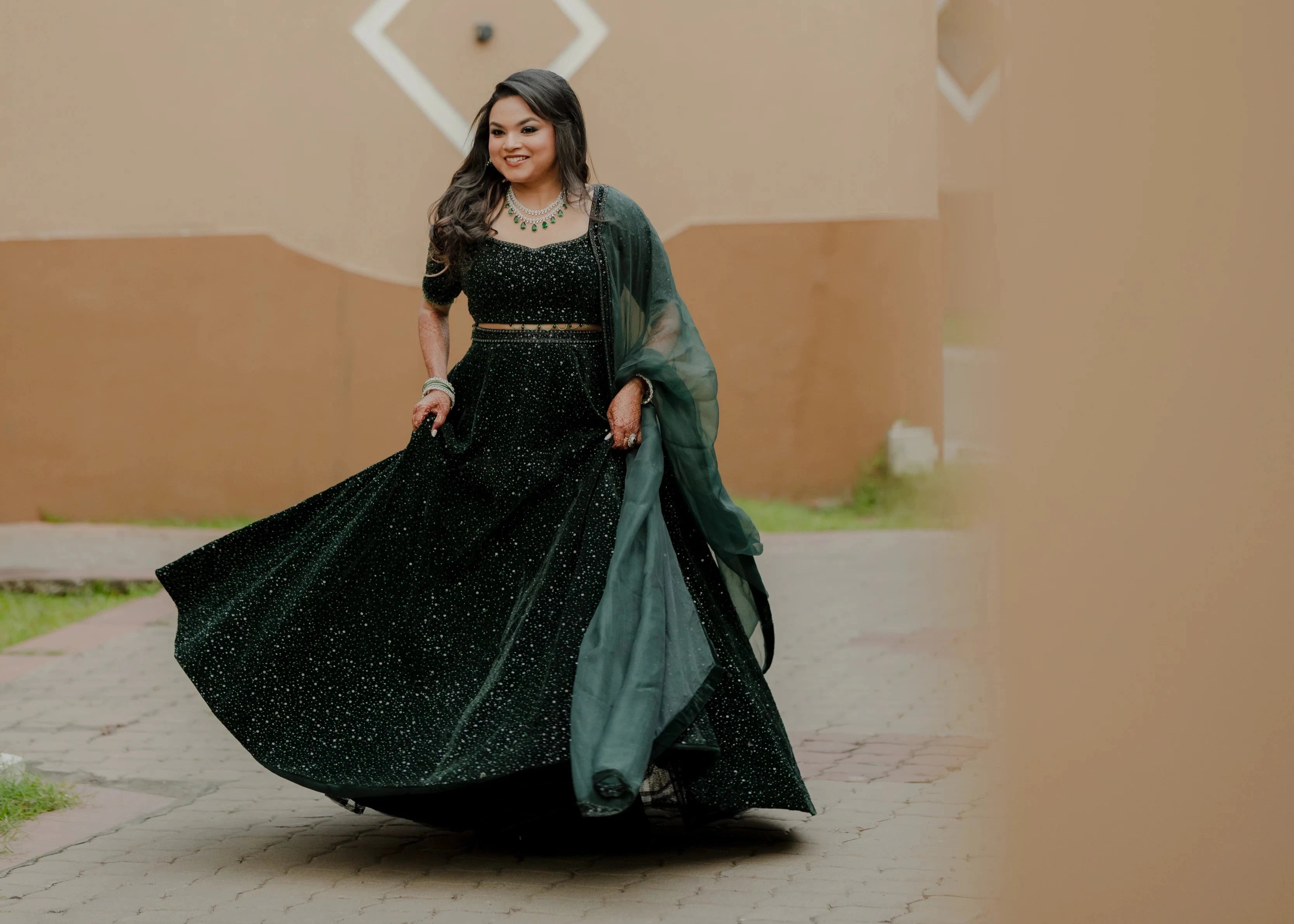 Bride Haripriya from USA twirling with a smile in a bottle green velvet lehenga, intricately handcrafted with sequins, cutdana, beads and crystals by team Archana Karthick.