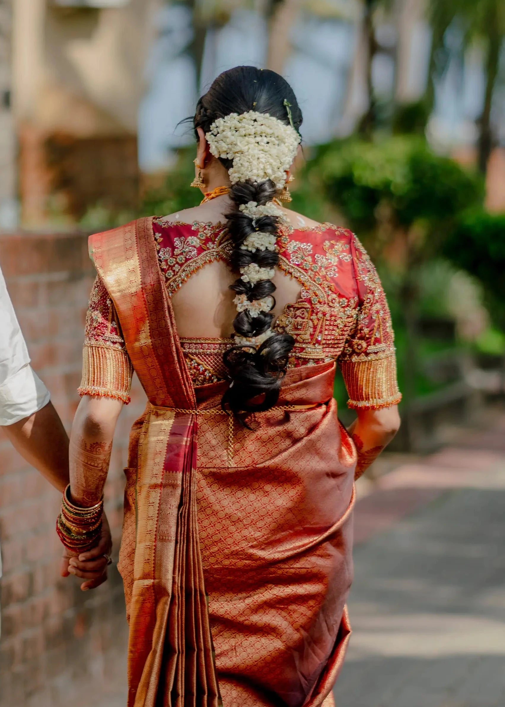 Bride Haripriya showcasing back blouse design in a red silk concept blouse for her wedding, handcrafted with zardozi, resham, stones, beads, crystals and cutdana by team Archana Karthick.