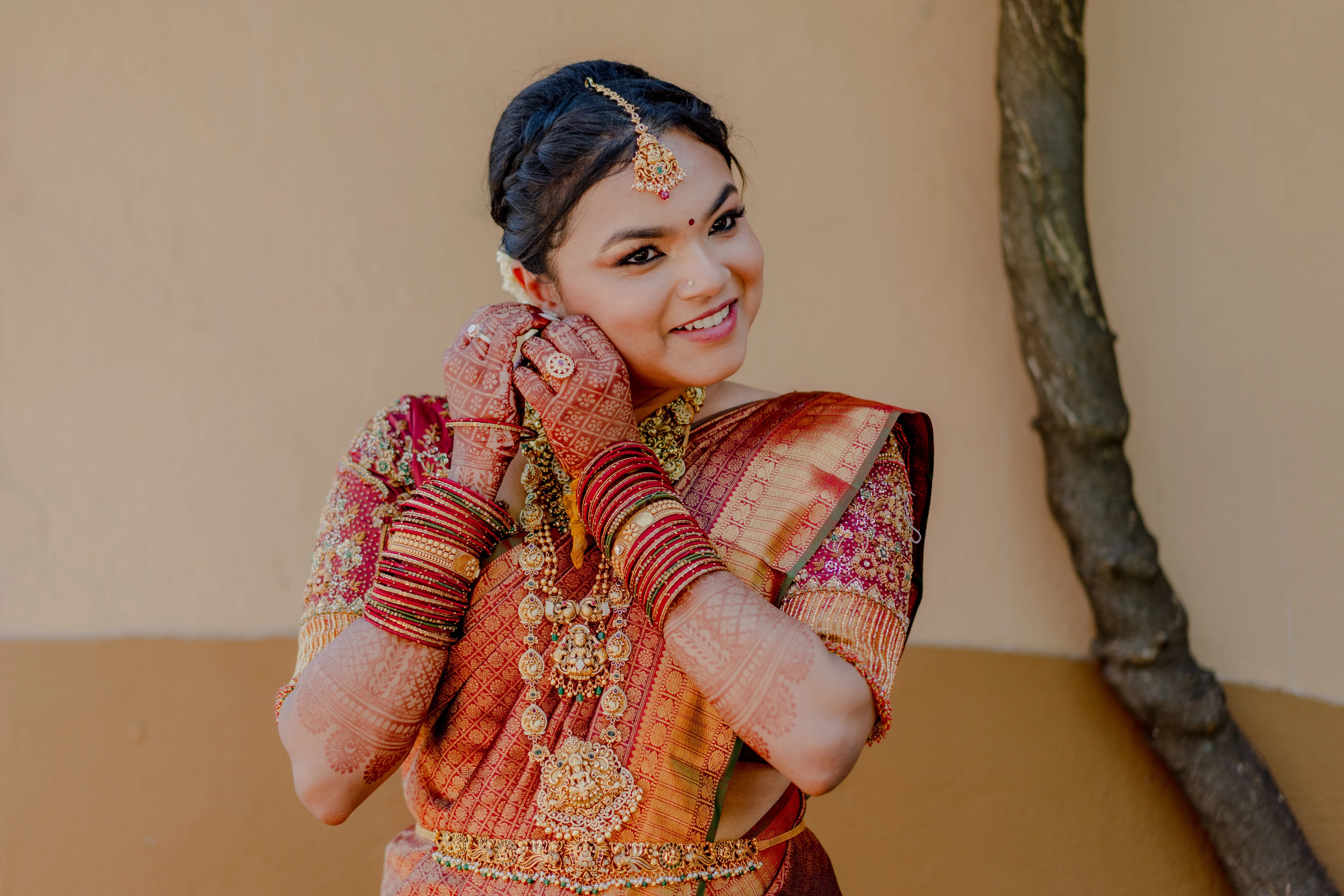 Bride Haripriya smiling in a red silk concept blouse for her wedding, handcrafted with zardozi, resham, stones, beads, crystals and cutdana by team Archana Karthick.