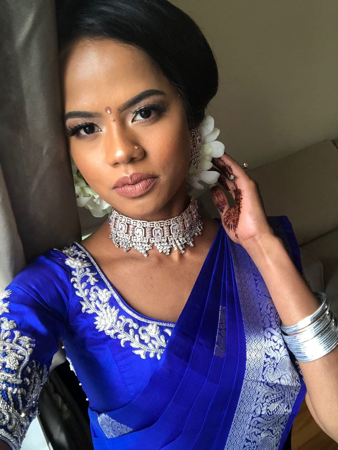 Bride Hemini from Canada smiling in a blue silk blouse handcrafted intricately with beads, pearls, resham and zardozi.
