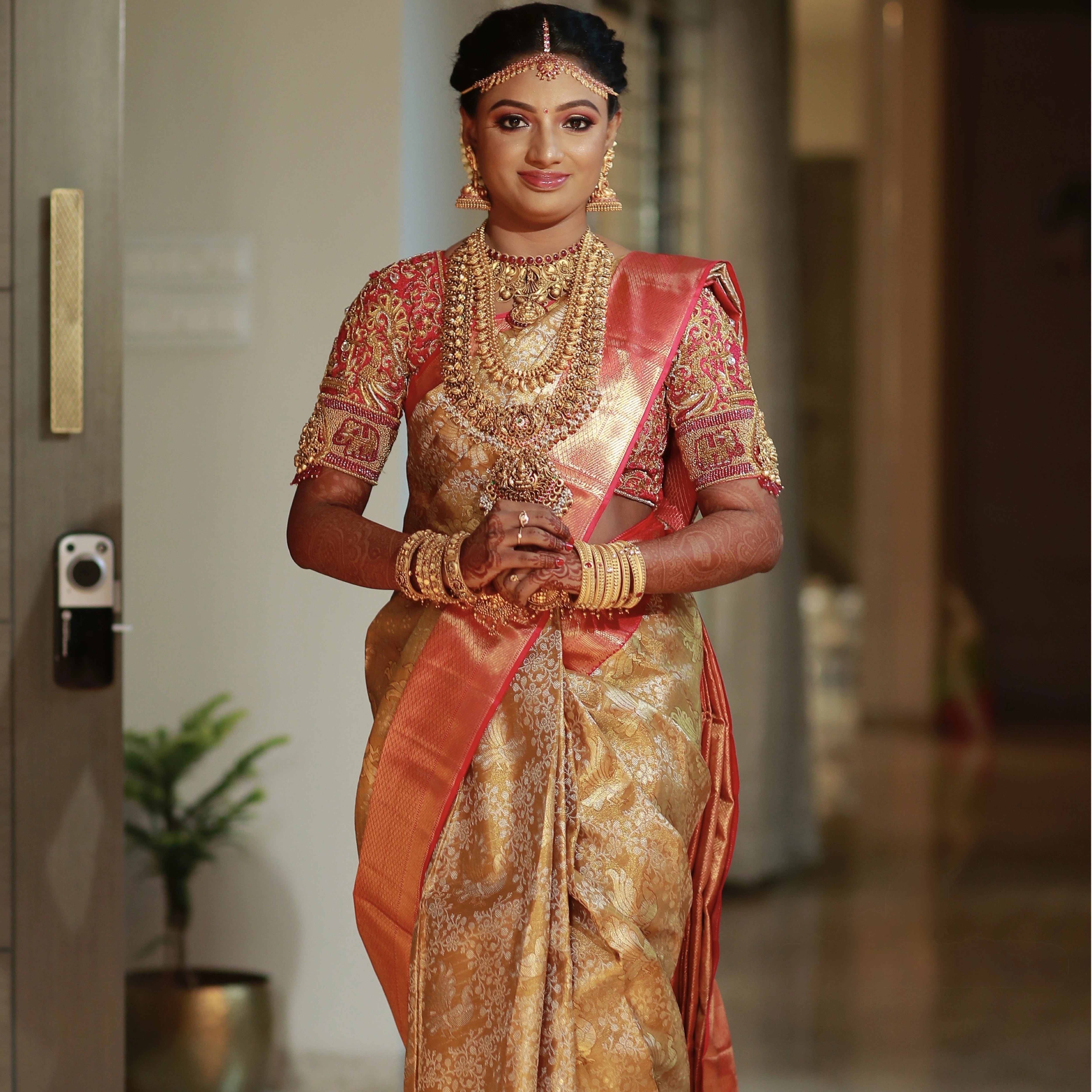 Bride Ishwarya in a red silk blouse handcrafted by team Archana Karthick.