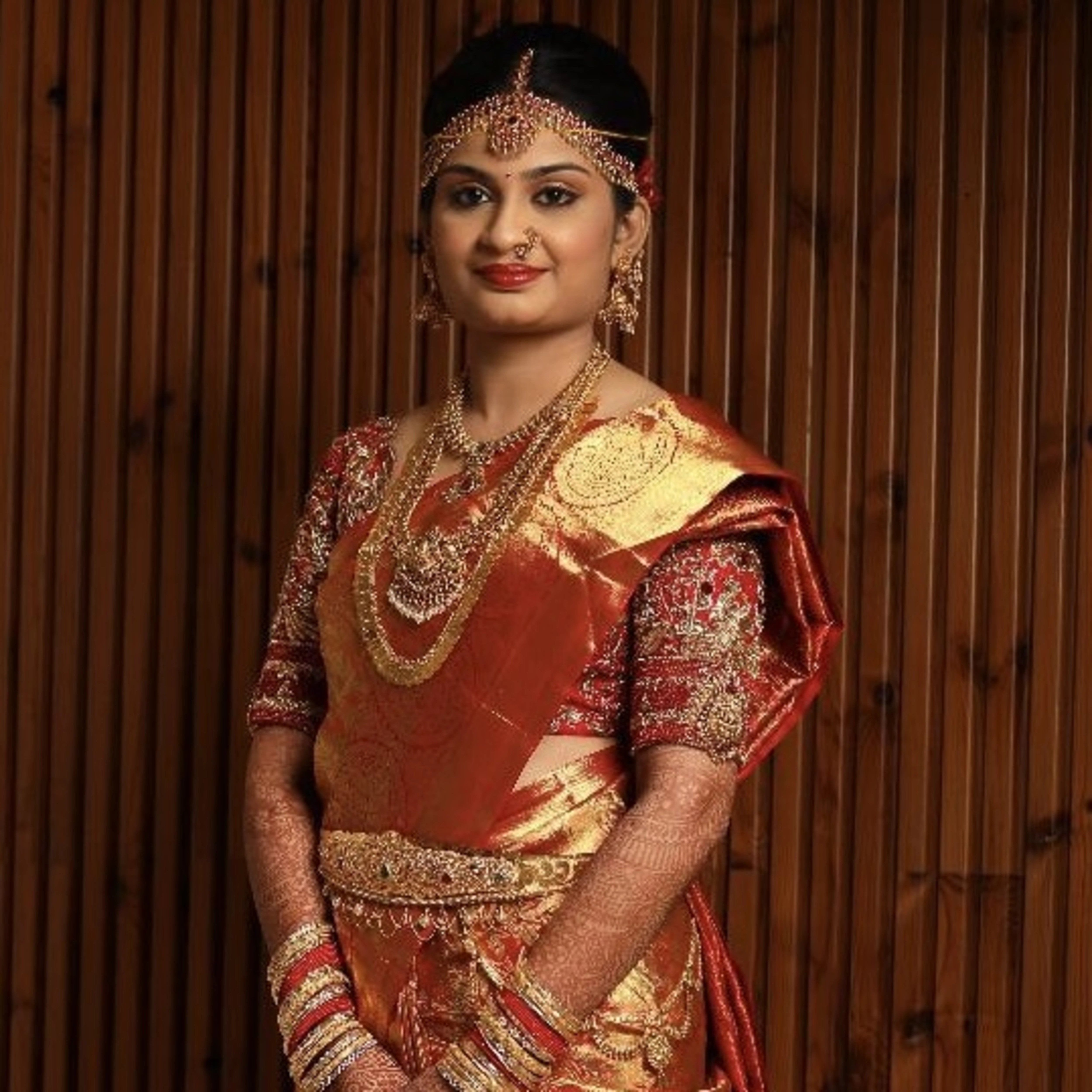 Bride Jashwanti Reddy posing in a red silk palanquin concept blouse for her wedding, handcrafted with zardozi, resham and beads by team Archana Karthick.