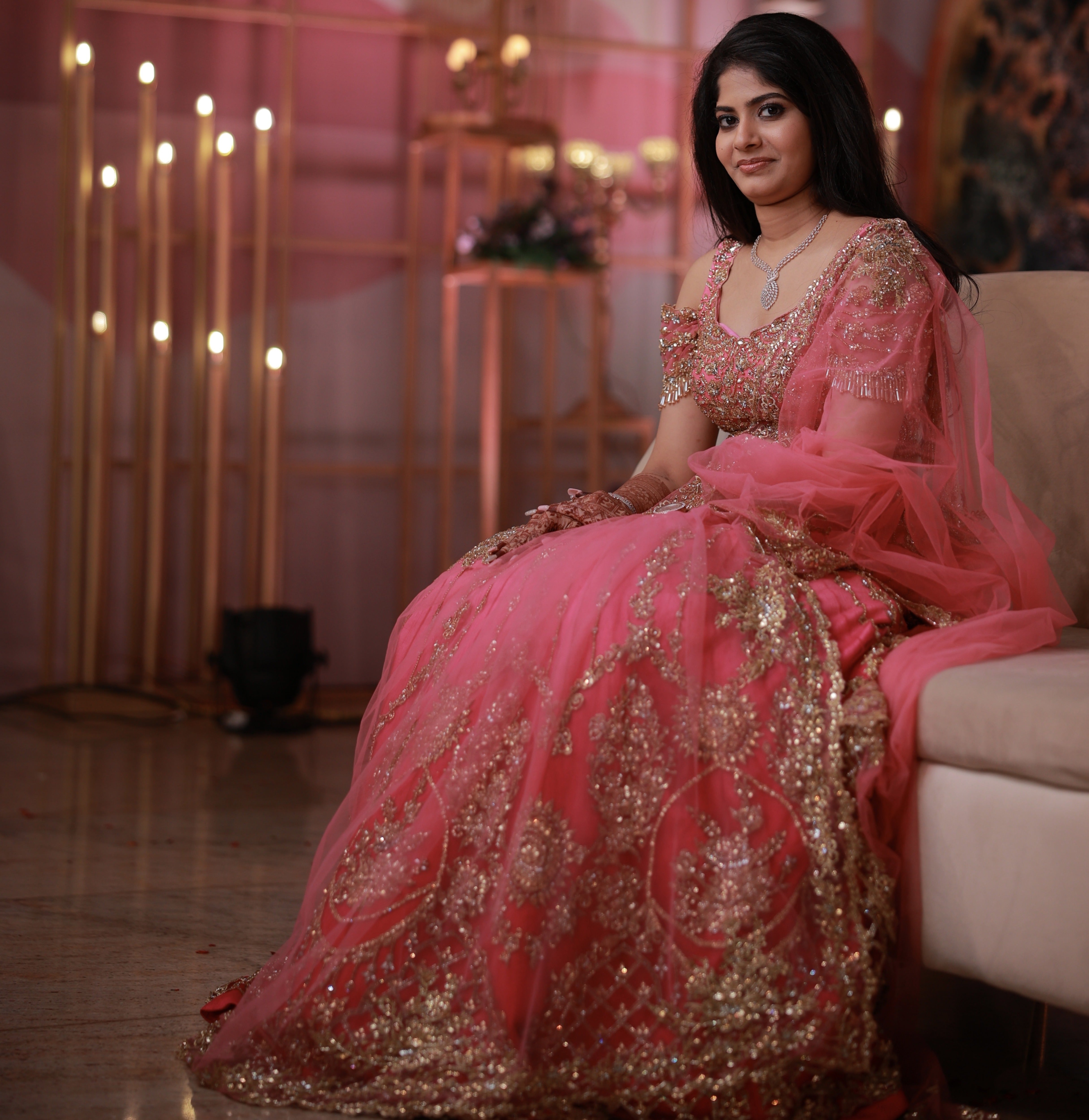 Bride Kaviya from Christchurch, New Zealand seated elegantly on the couch in her pink handcrafted reception lehenga with heavy stone work designed by Archana Karthick. Front blouse and lehnega design is captured well.