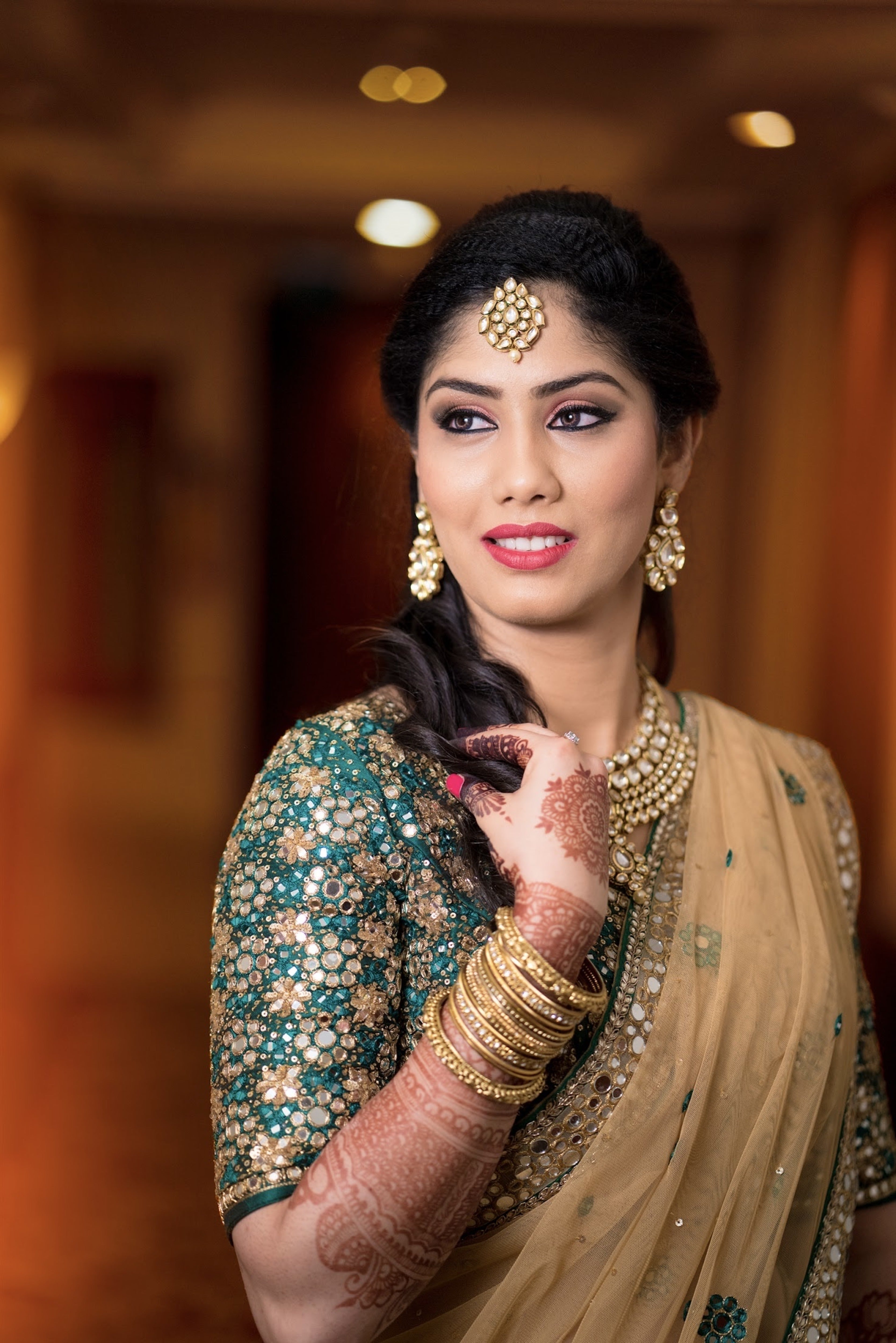 Bride Keerthana, from new zealand in a green handcrafted love story lehenga by Archana Karthick. Closeup picture shows her sleeve mirror work