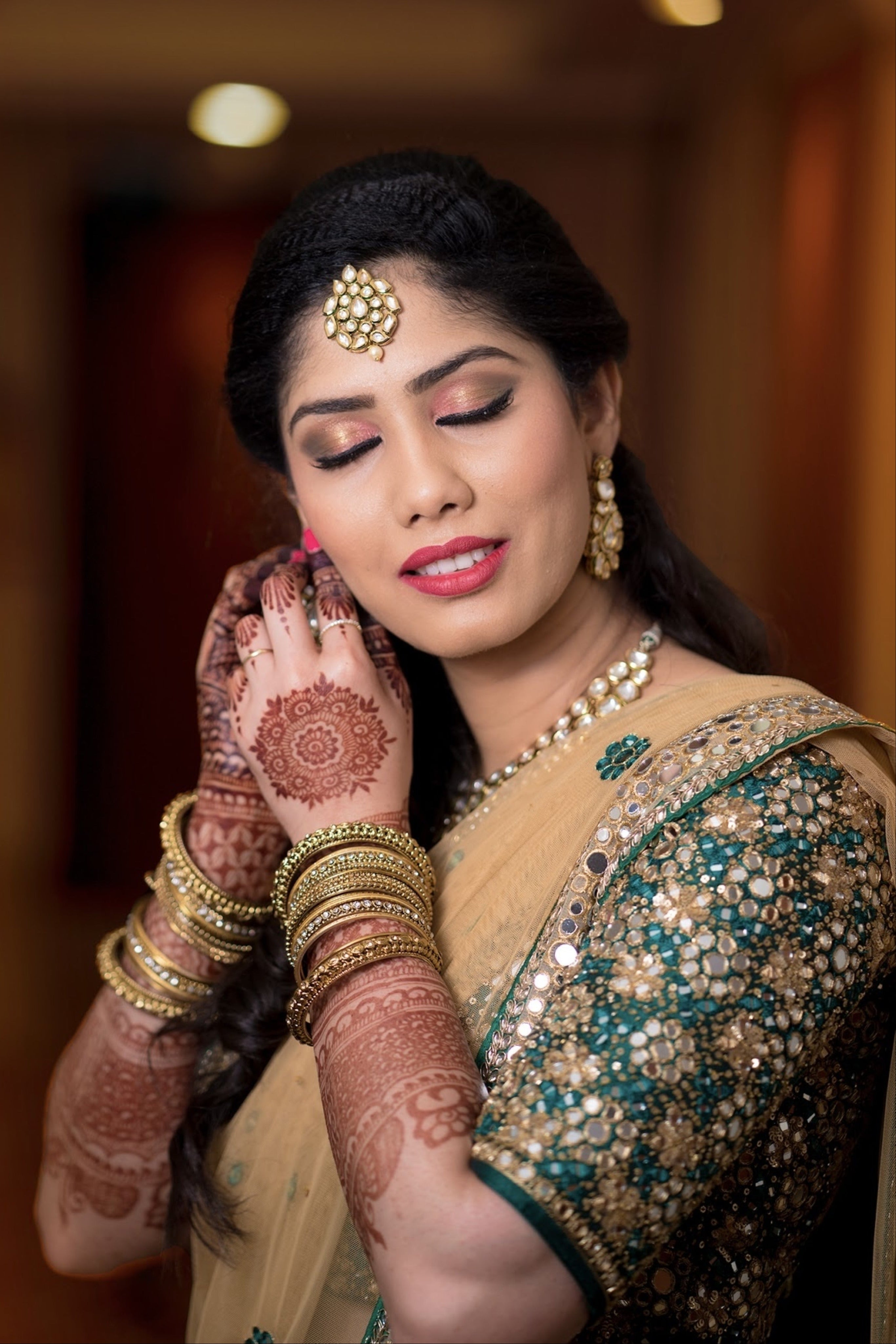 Bride Keerthana, from new zealand in a green handcrafted love story lehenga by Archana Karthick. Closeup shot of her wearing her ear rings
