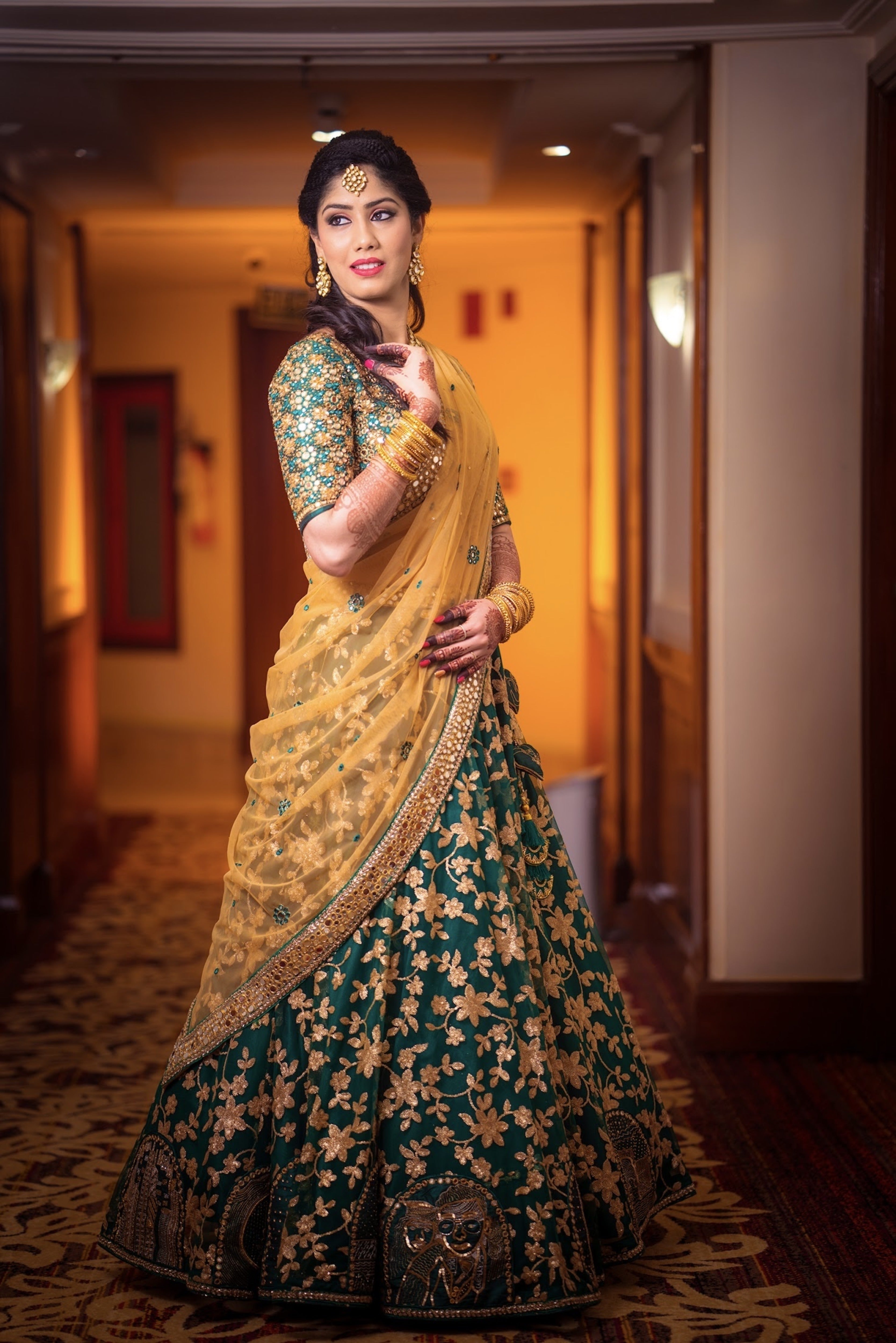 Bride Keerthana, from new zealand in a green handcrafted love story lehenga by Archana Karthick. she is posing looking to her right.