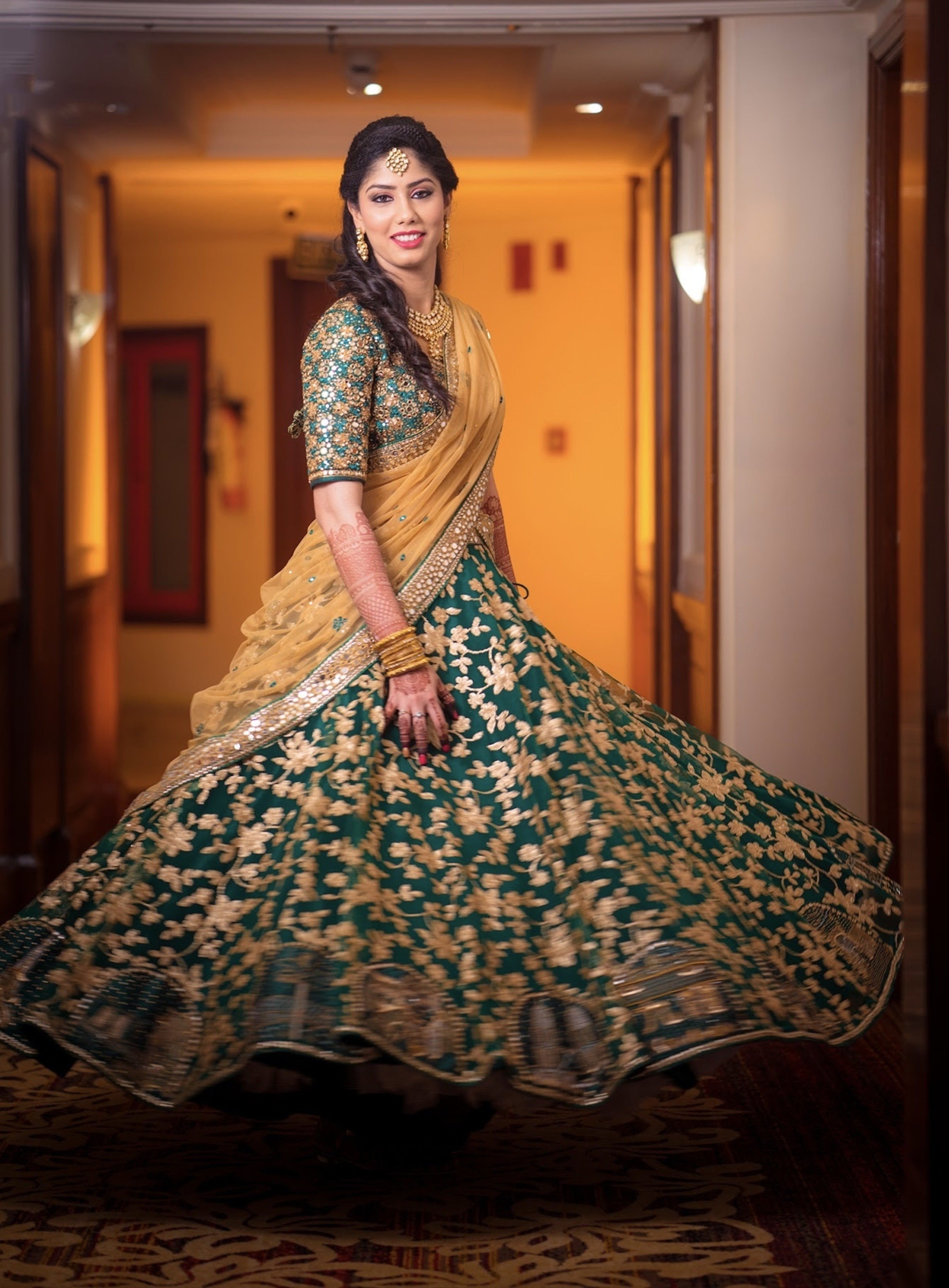 Bride Keerthana, from new zealand in a green handcrafted love story lehenga by Archana Karthick. she is twirling with a smile.