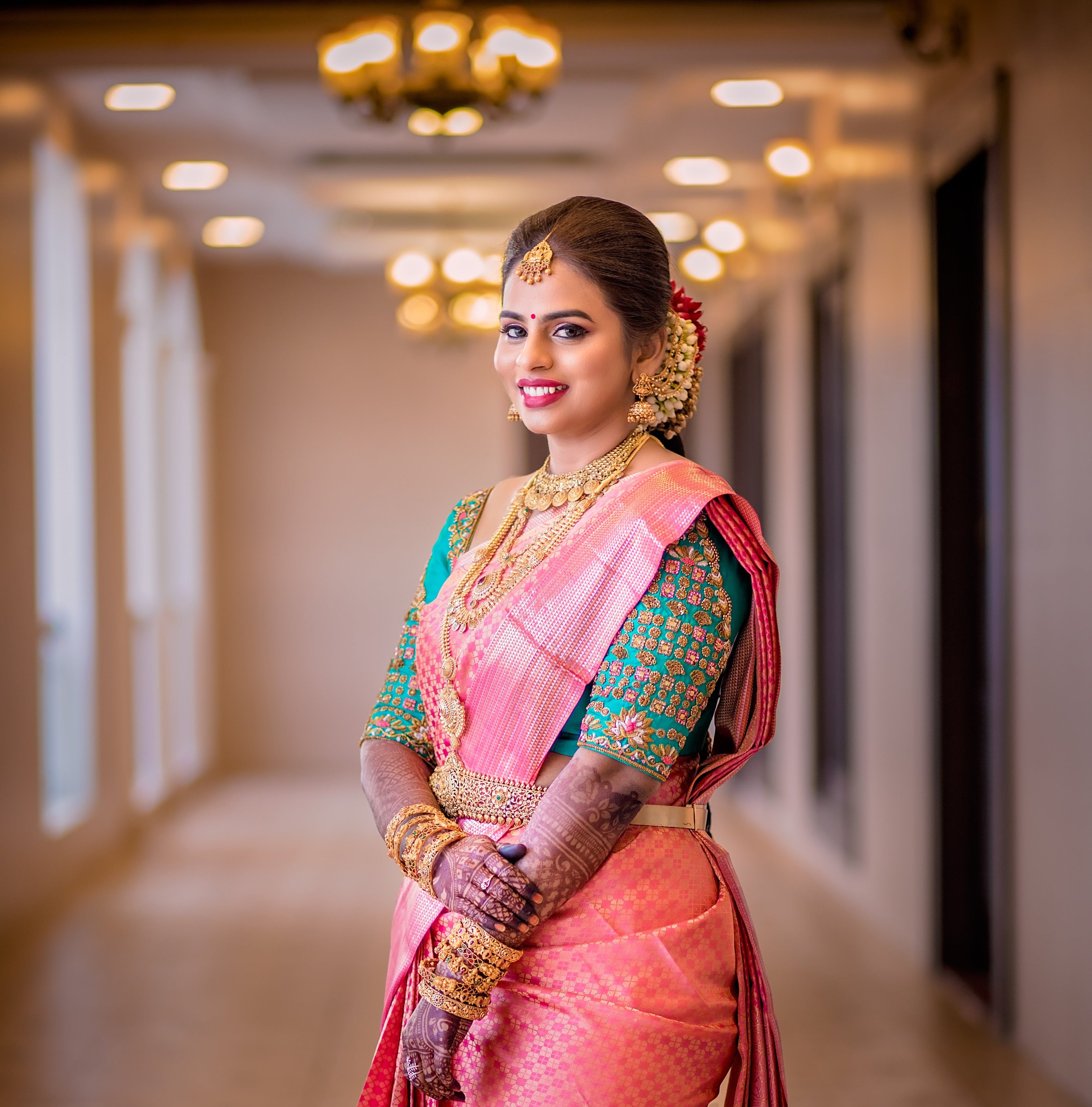 Bride Kowsalya from USA in a teal raw silk blouse designed by Archana Karthick. Posing for a side profile of blouse sleeves.