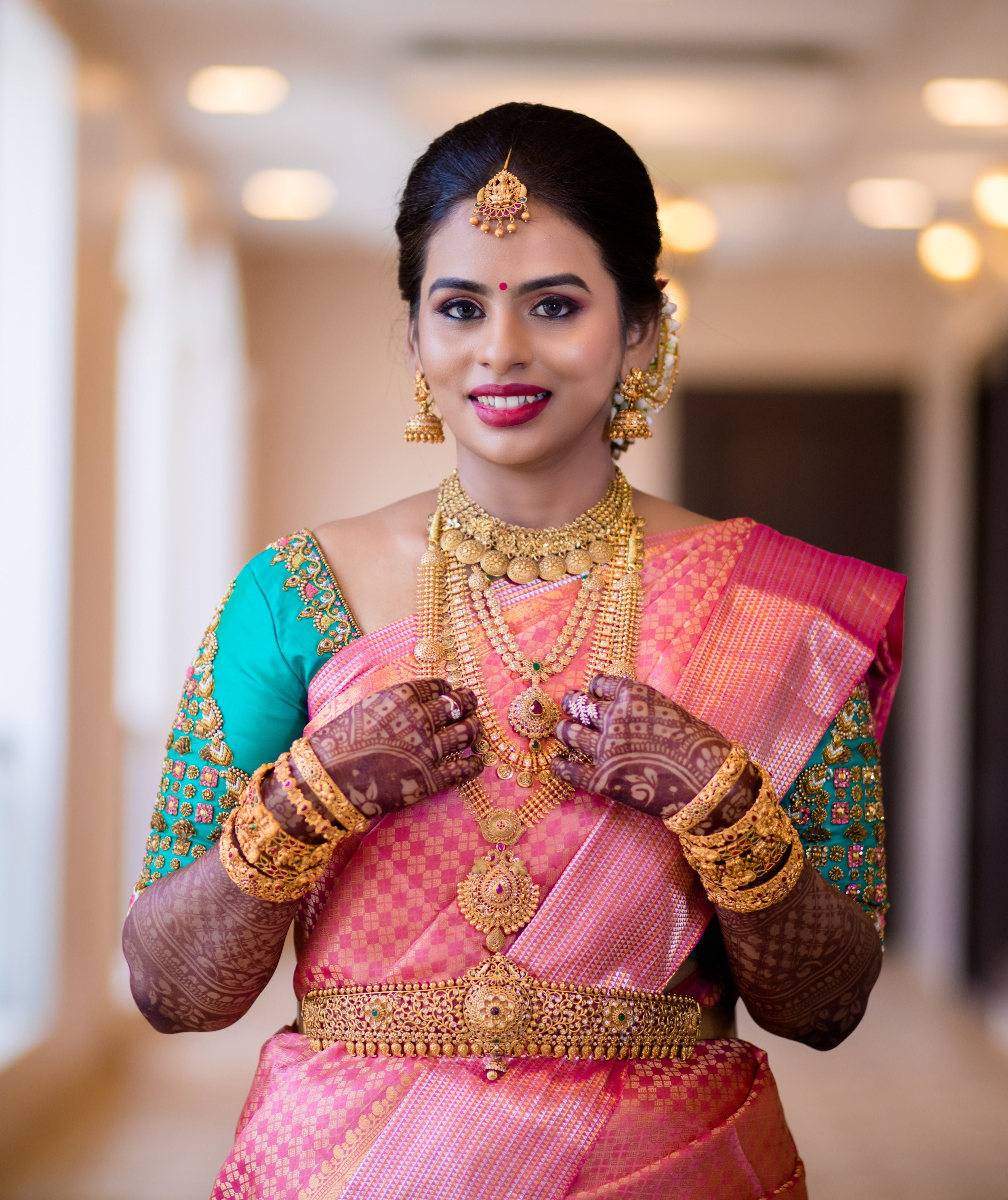 Bride Kowsalya from USA in a teal raw silk blouse designed by Archana Karthick. Posing looking straight at the camera.