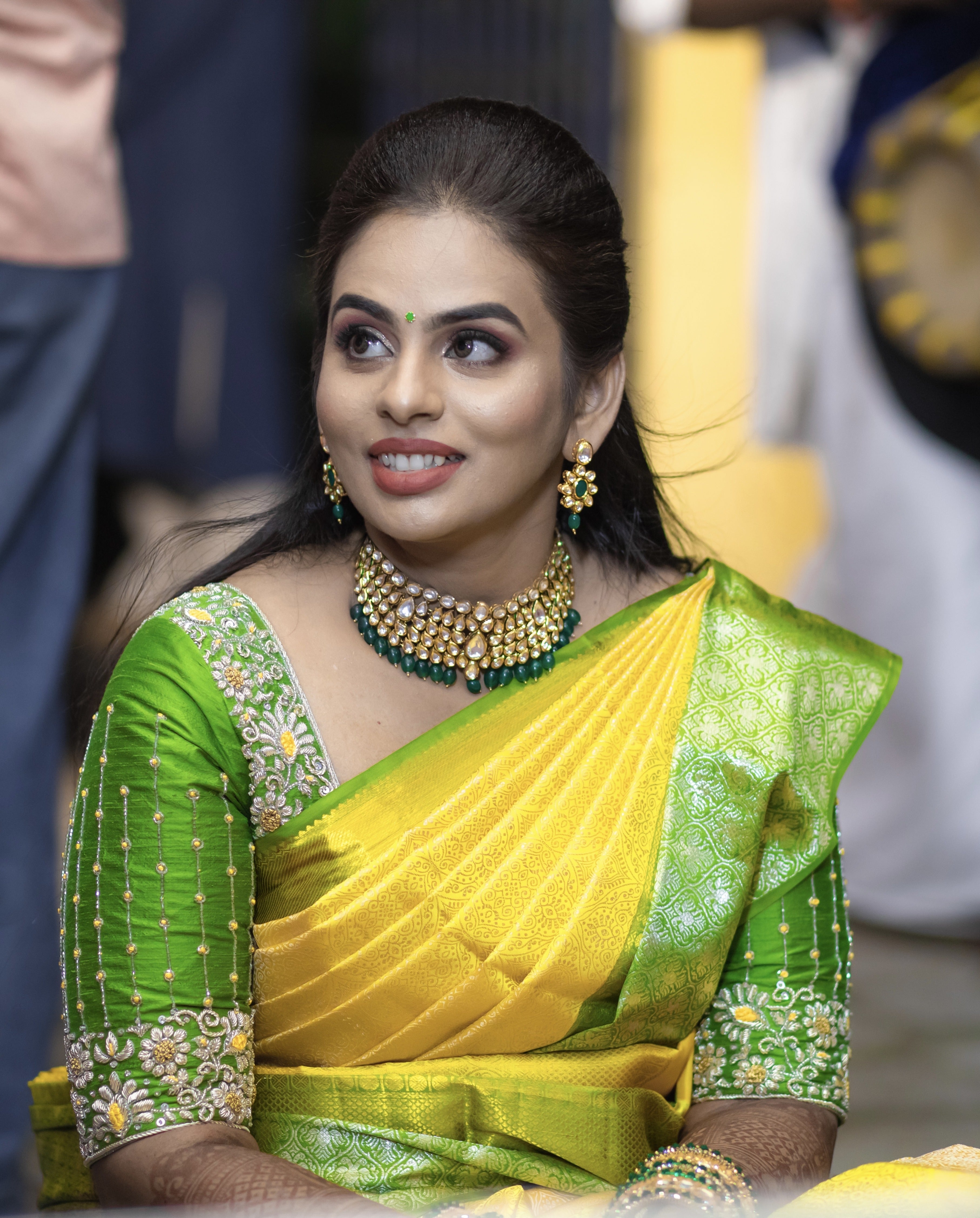 Bride Kowsalya in a handcrafted green silk blouse by Archana Karthick. Posing seated looking to her right.