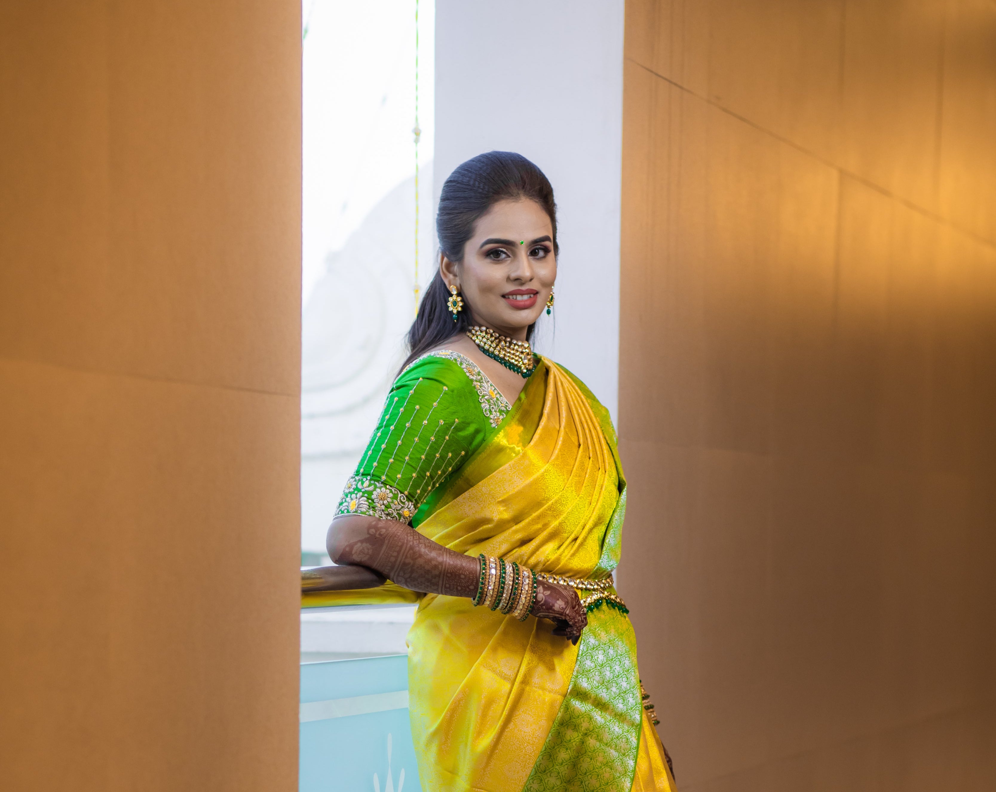 Bride Kowsalya in a handcrafted green silk blouse by Archana Karthick. Posing to her right.