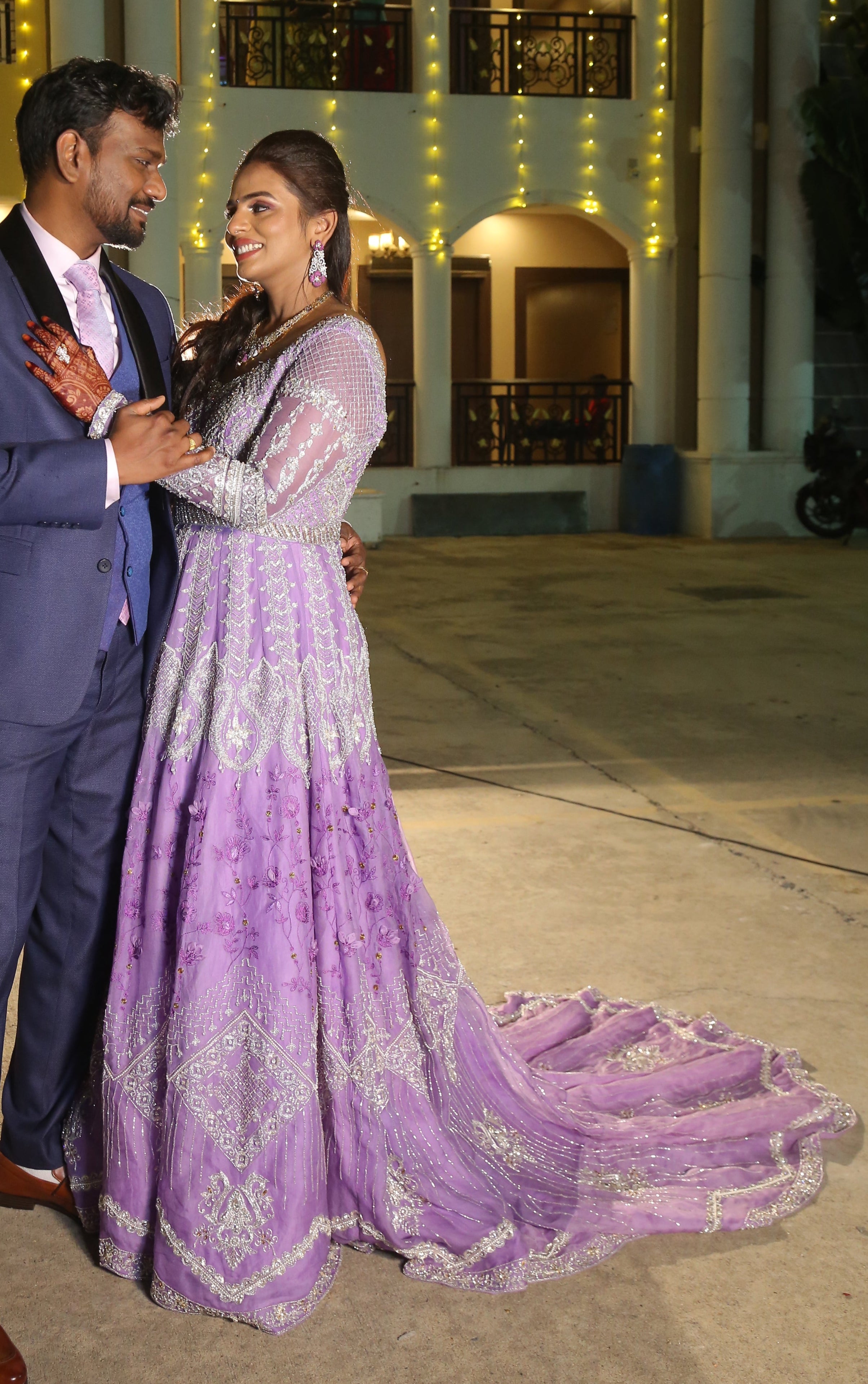 Bride Kowsalya in handcrafted lavender bridal gown designed by Archana Karthick. Full side profile pose with groom.