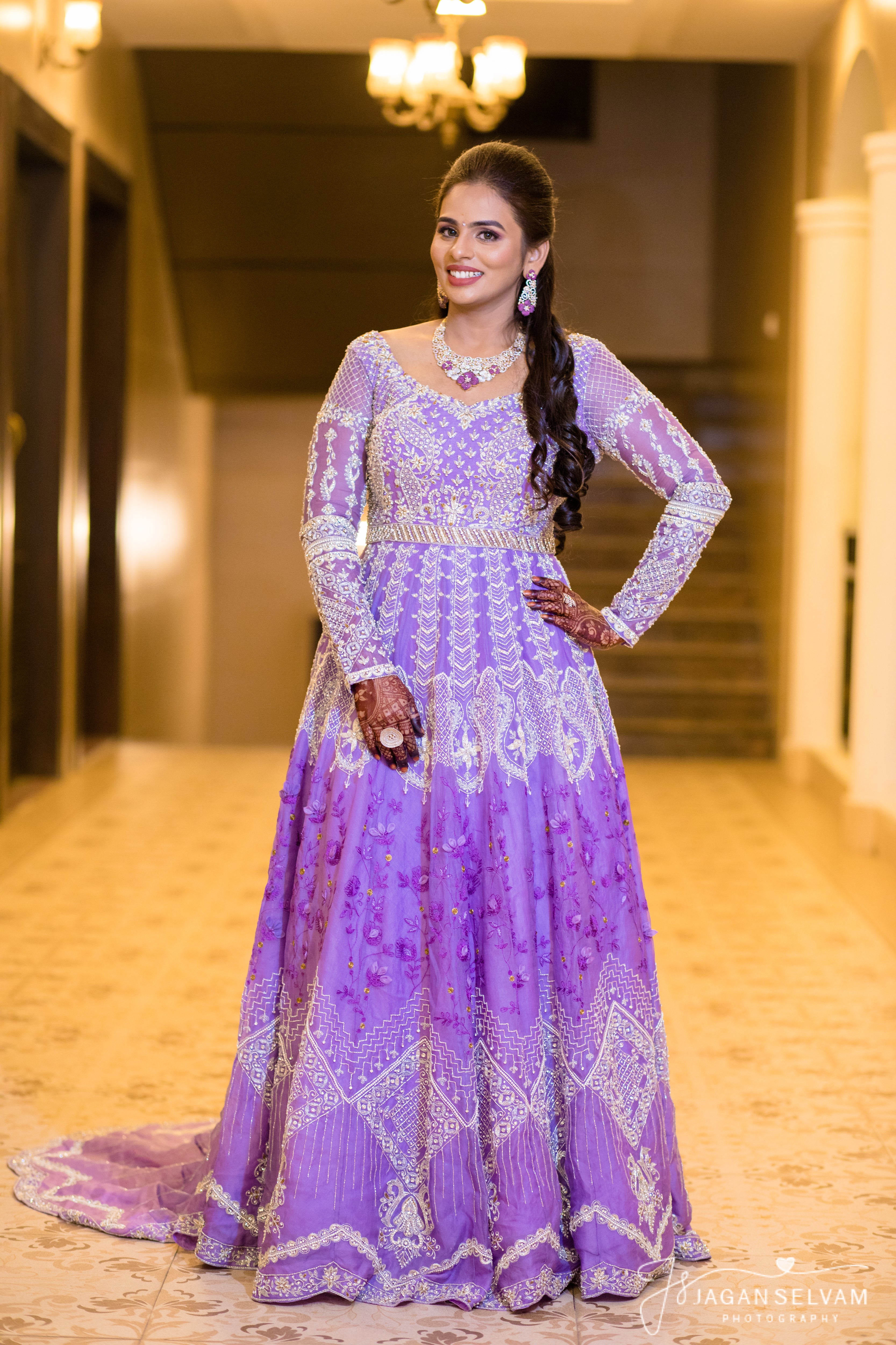 Bride Kowsalya in handcrafted lavender bridal gown designed by Archana Karthick. Looking straight at the camera full profile.