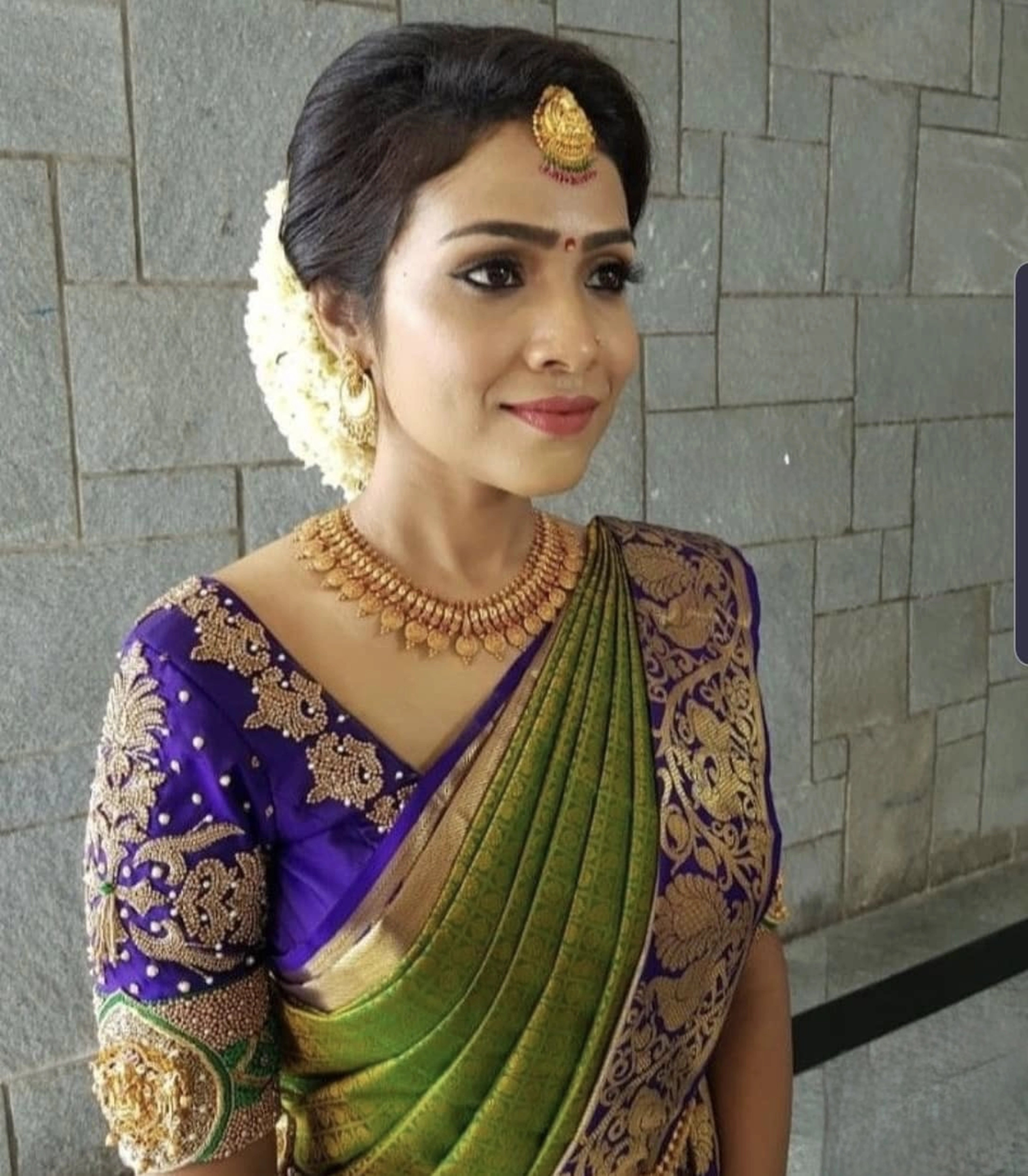 Bride Krishnapriya from Chennai posing for a photo in a blue silk blouse handcrafted intricately with beads, stones, resham and zardozi by team Archana Karthick.