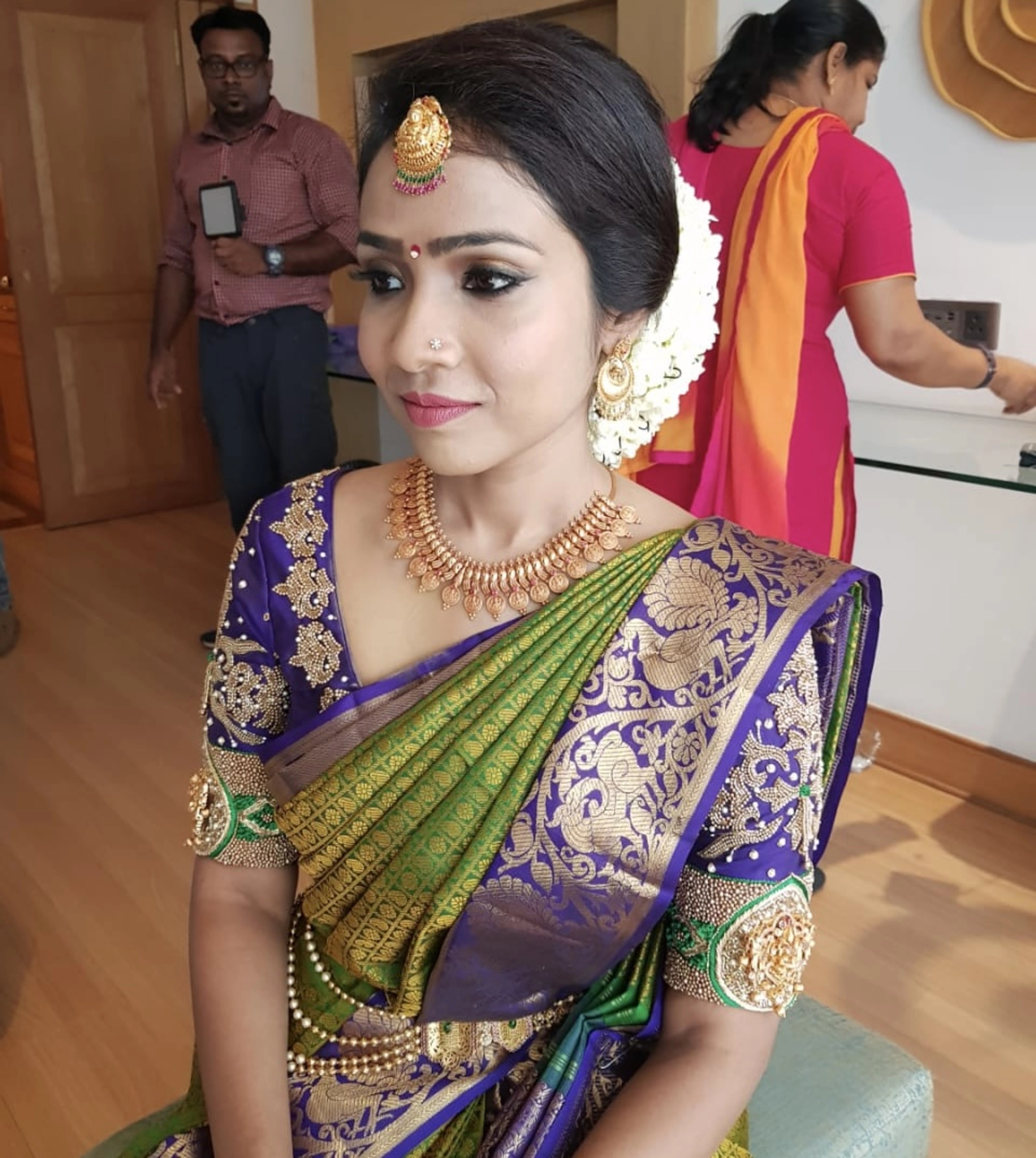 Bride Krishnapriya from Chennai posing seated in a blue silk blouse handcrafted intricately with beads, stones, resham and zardozi by team Archana Karthick.