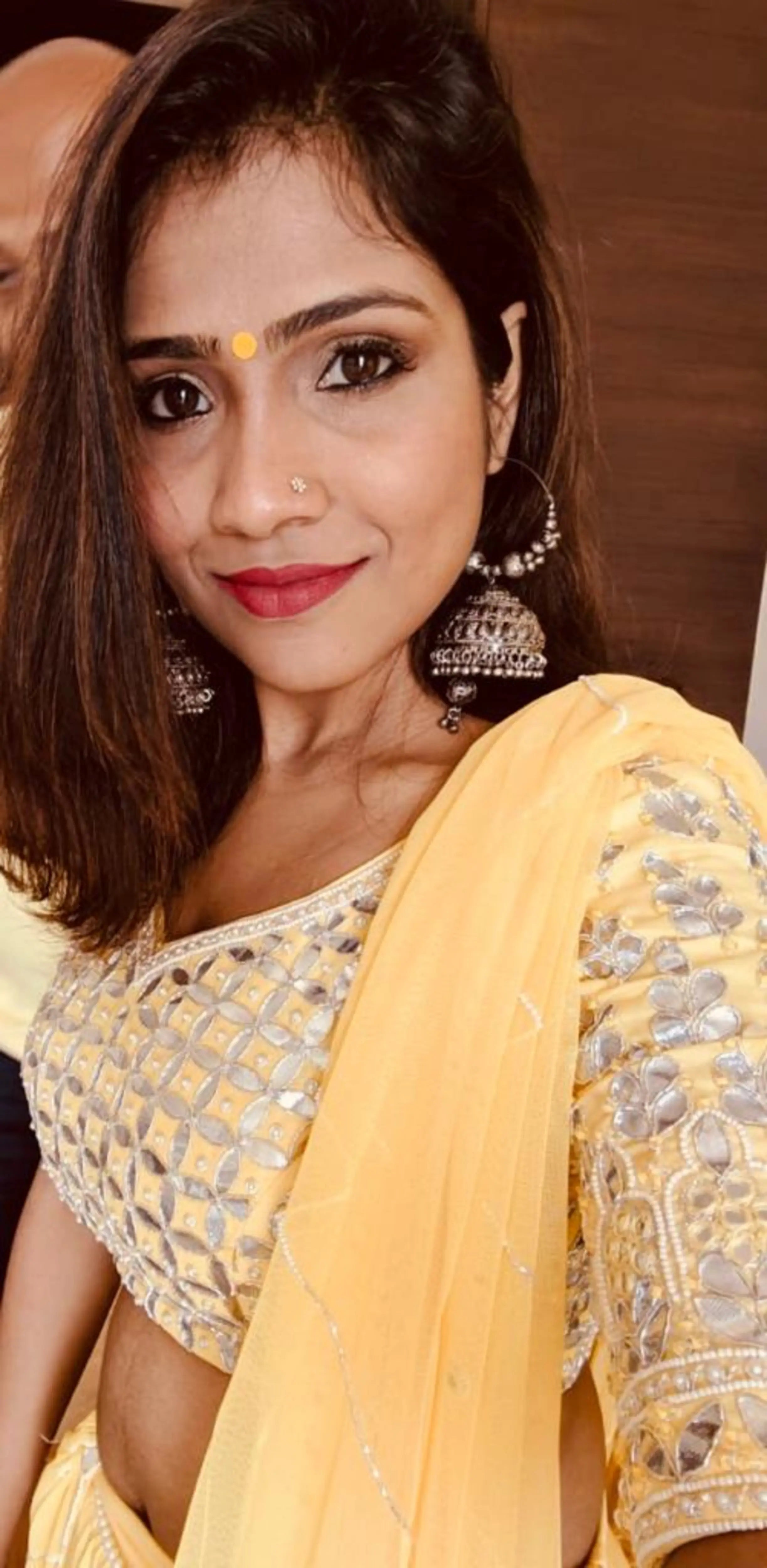 Bride Krishnapriya tking a selfie in a yellow lehenga by Archana Karthick.
