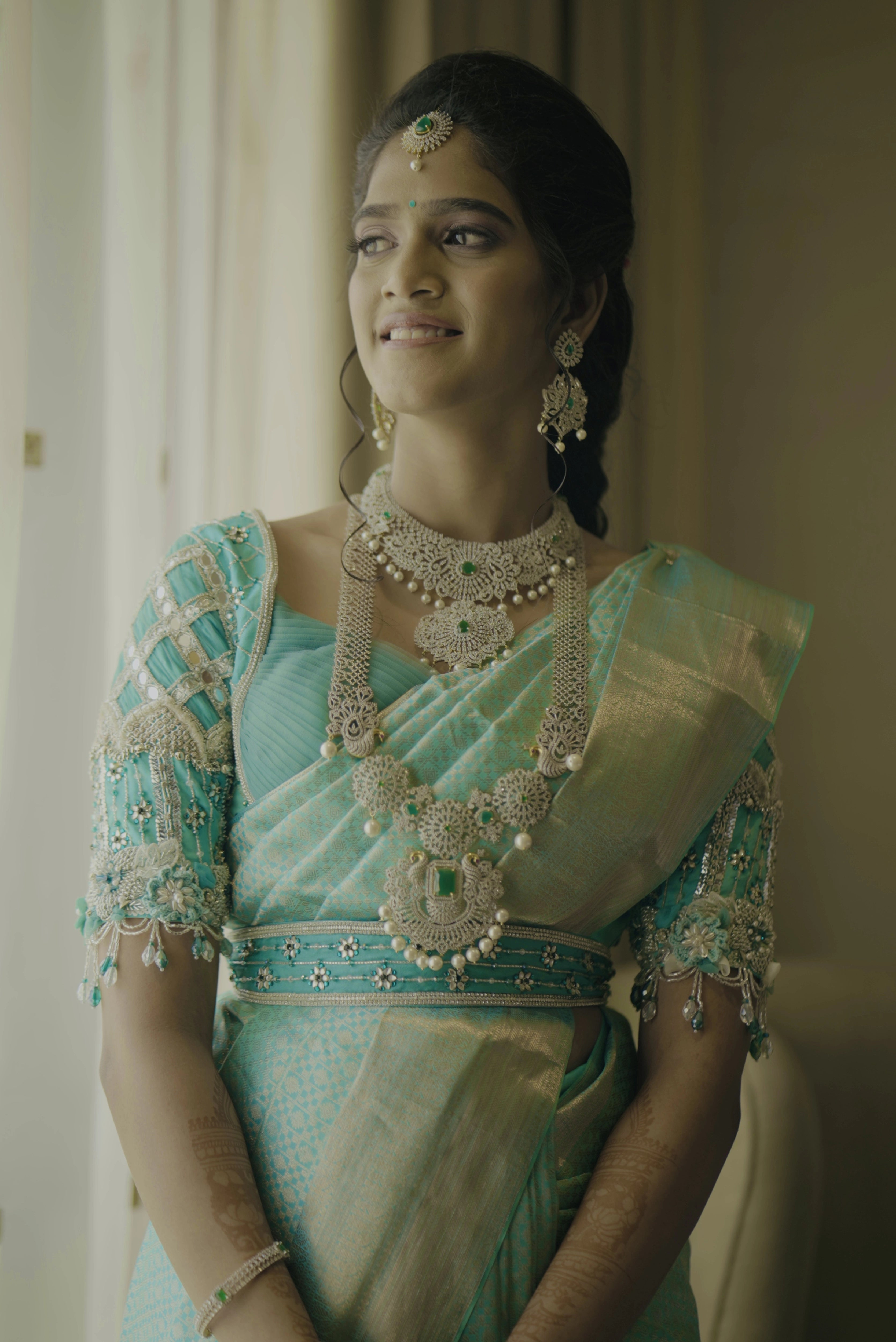 Bride Krithika in a blue raw silk blouse, intricately handcrafted with 3D flowers, zari, cutdana, zardozi, crystals, mukaish and mirror by team Archana Karthick