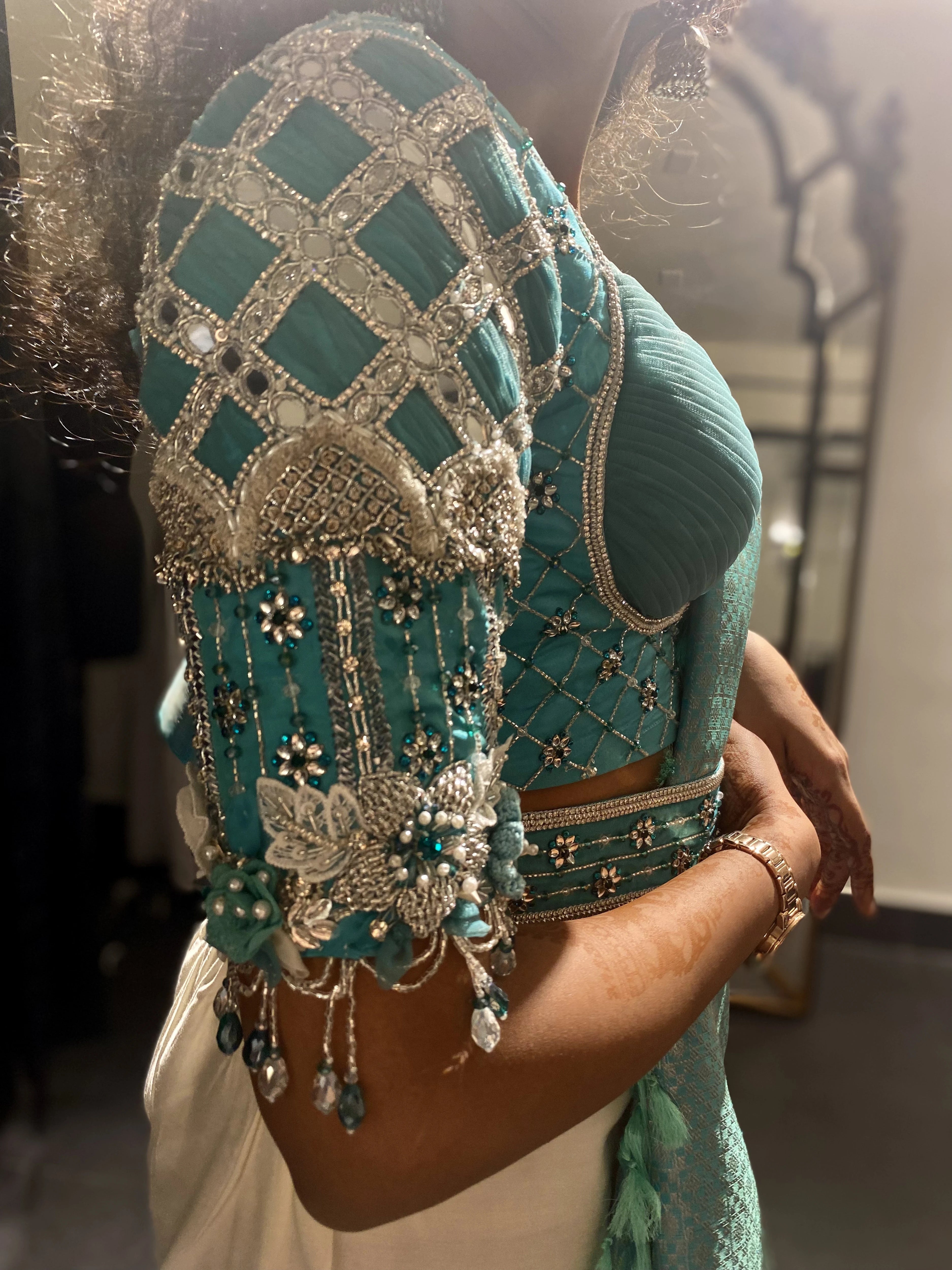Bride Krithika showcasing sleeve in a blue raw silk blouse, intricately handcrafted with 3D flowers, zari, cutdana, zardozi, crystals, mukaish and mirror by team Archana Karthick
