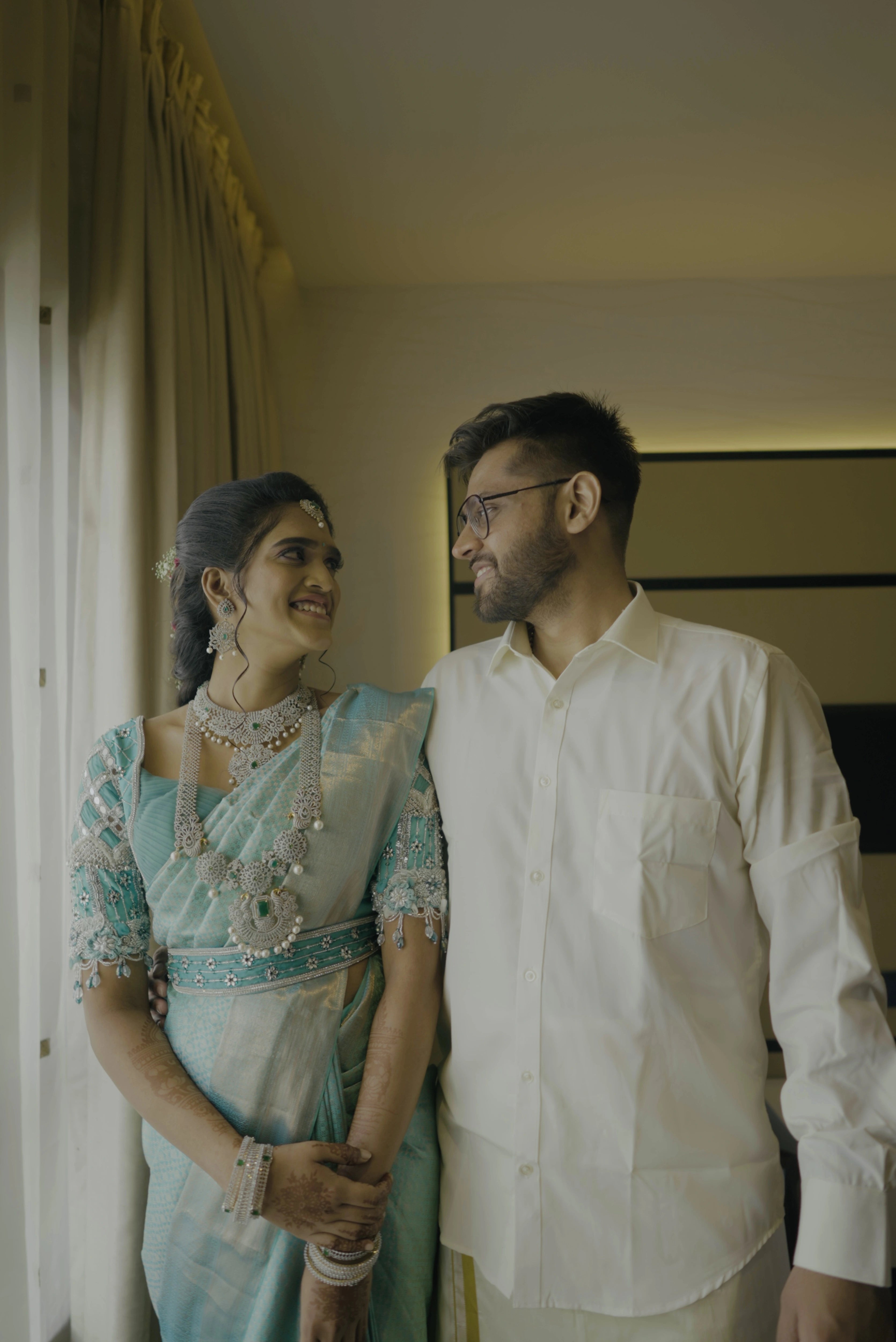 Bride Krithika with groom in a blue raw silk blouse, intricately handcrafted with 3D flowers, zari, cutdana, zardozi, crystals, mukaish and mirror by team Archana Karthick