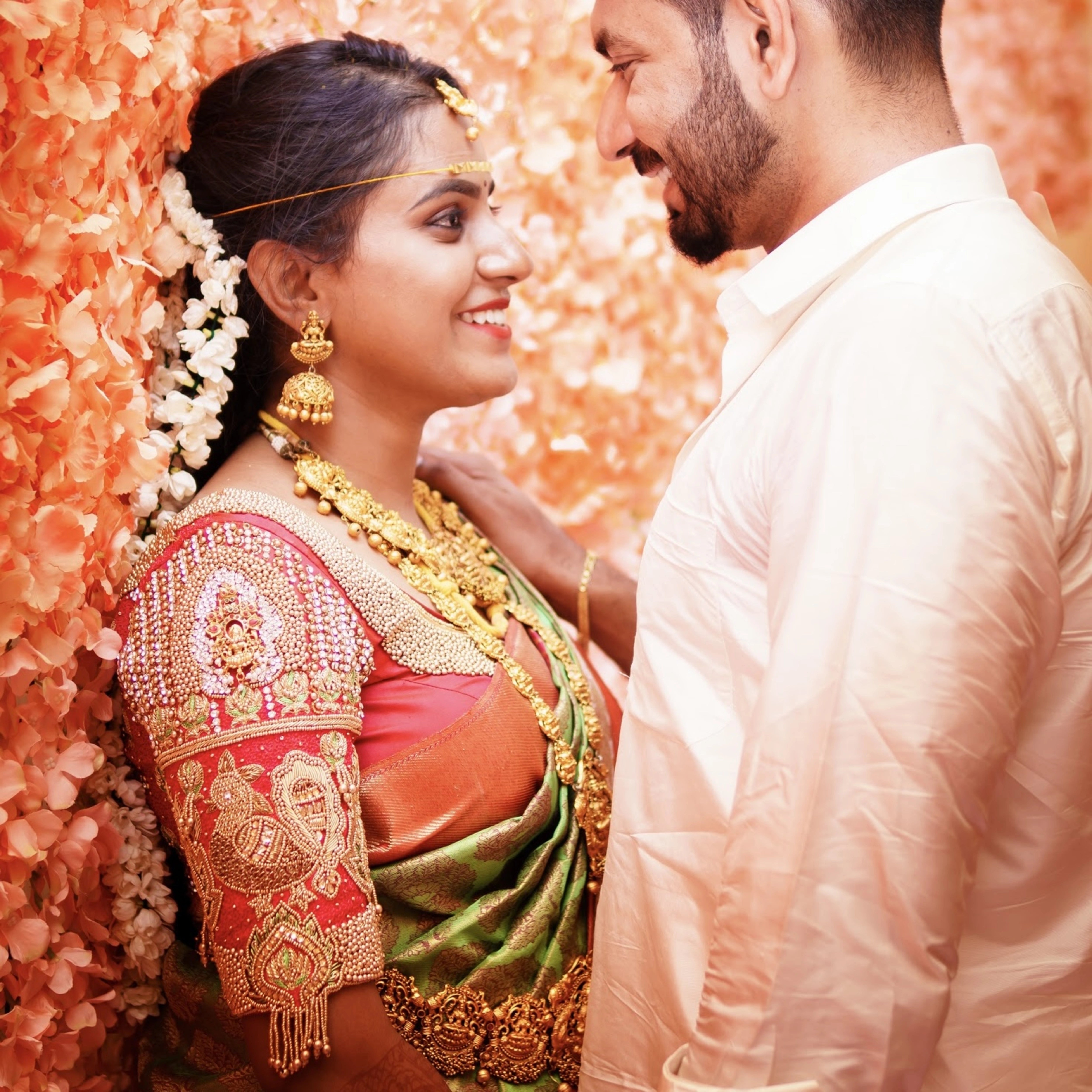 Bride Lavanya S smiling in a handcrafted red silk blouse embellished with beads, zardozi, stones, beads, resham knot work & goddess pendants by team Archana Karthick.