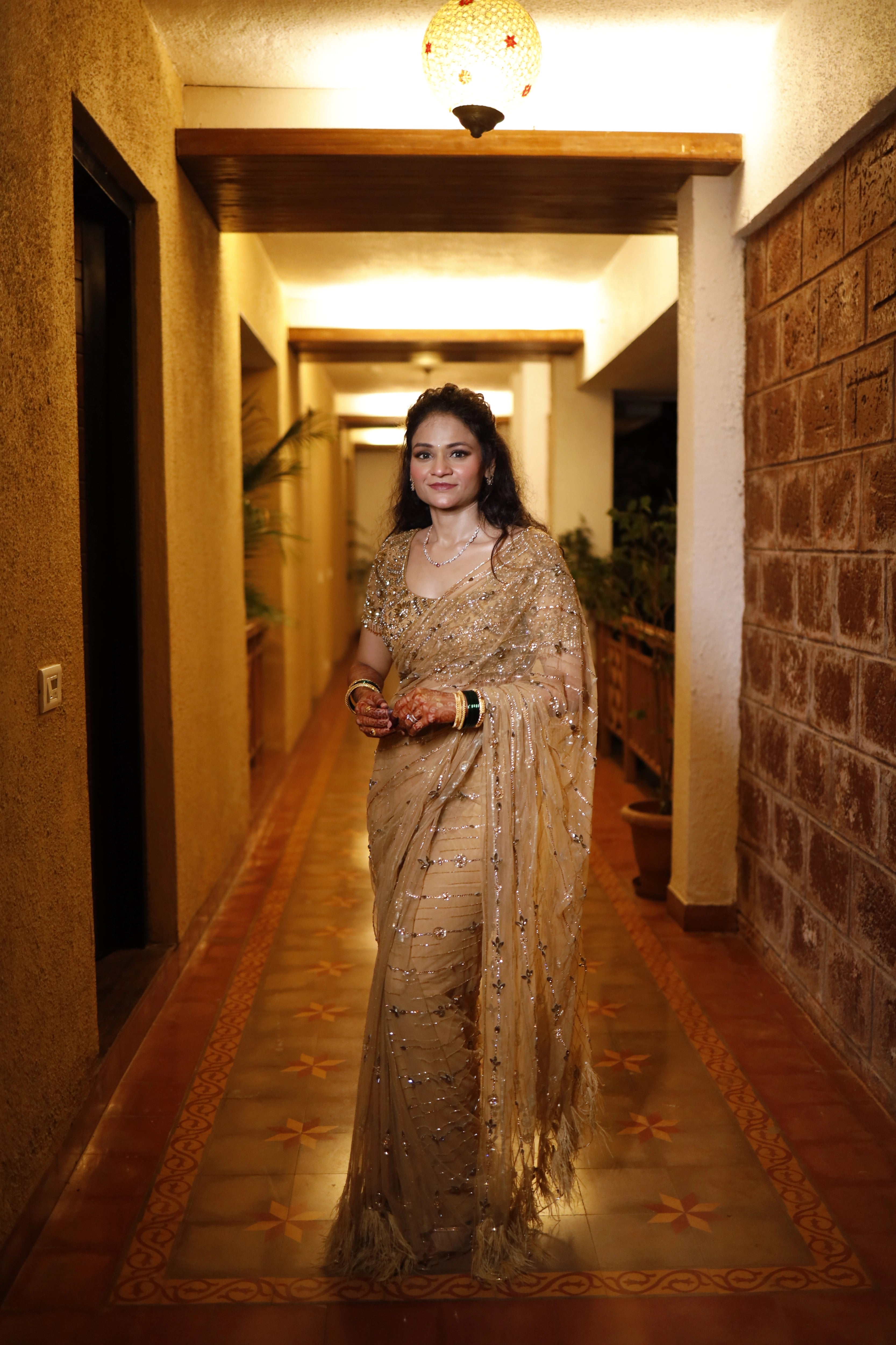Bride Neha from Virginia, posing in a golden tulle saree, handcrafted with rhinestones, zardozi, sequins, crystals, cutdana and stones by team Archana Karthick.