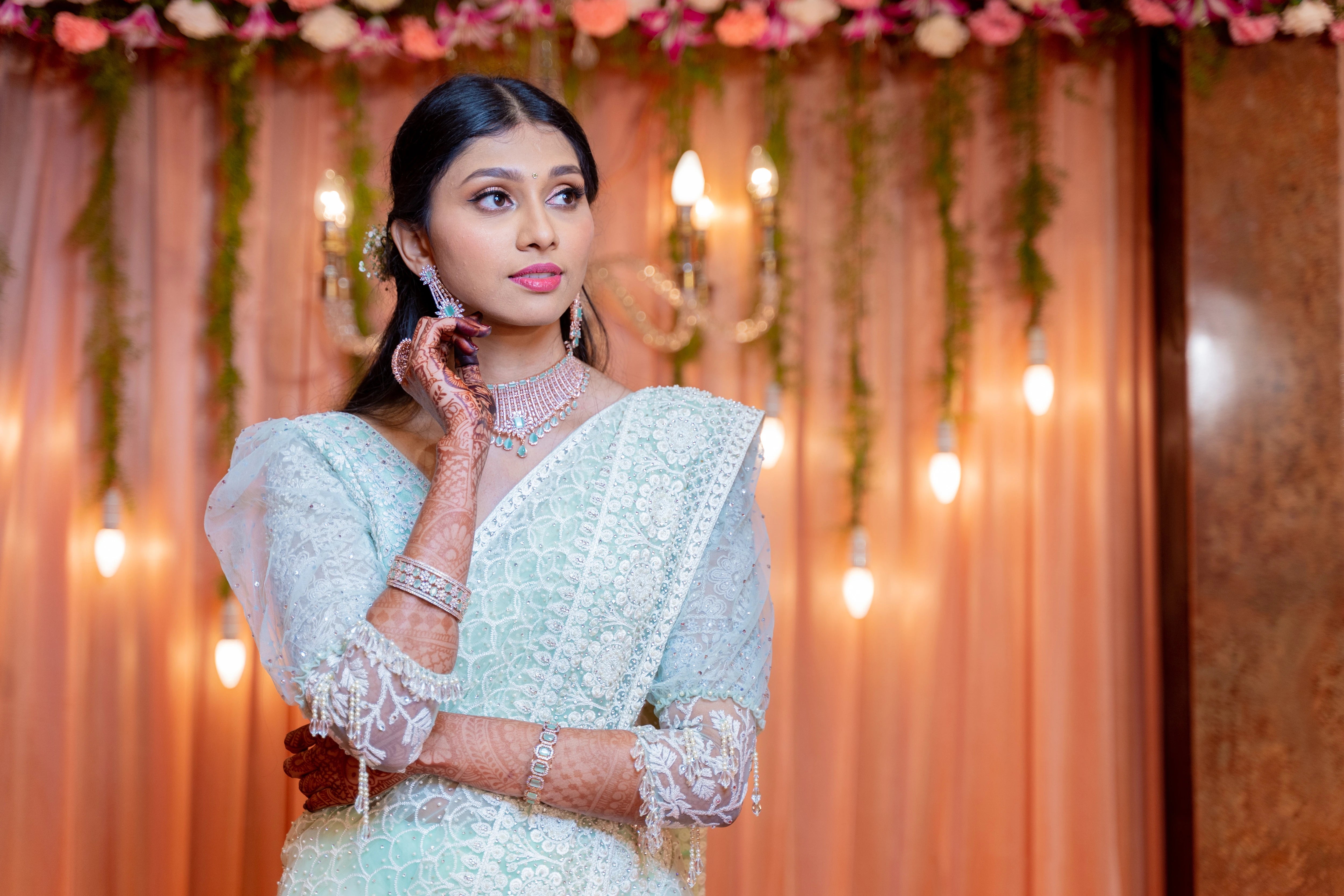 Bride Niveditha posing for photo in a pastel mint green tulle blouse handcrafted by team Archana Karthick.