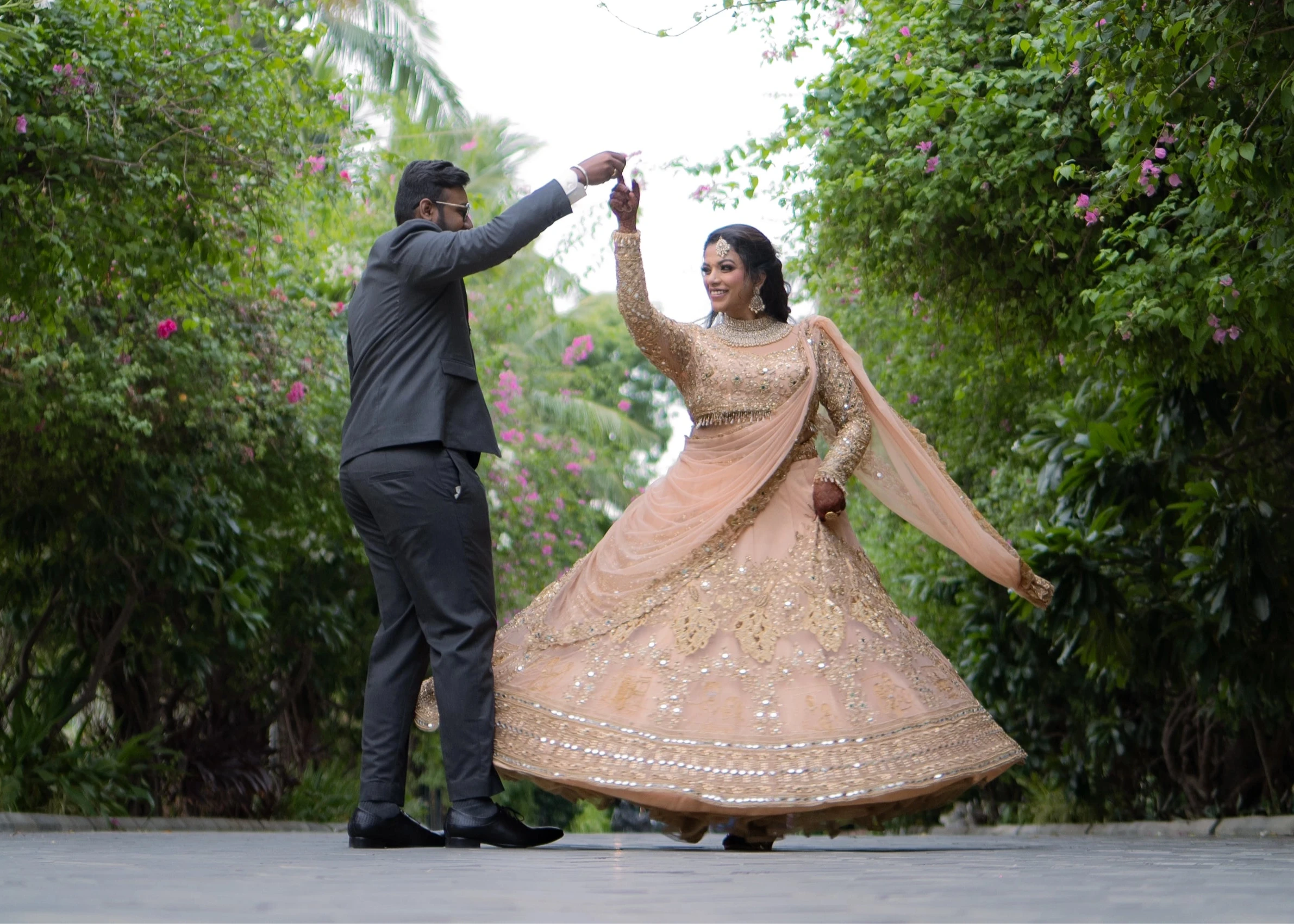 Bride Pavithra & Groom Jai in a beige gold lehenga and charcoal grey suit and intricately handcrafted by team Archana Karthick.