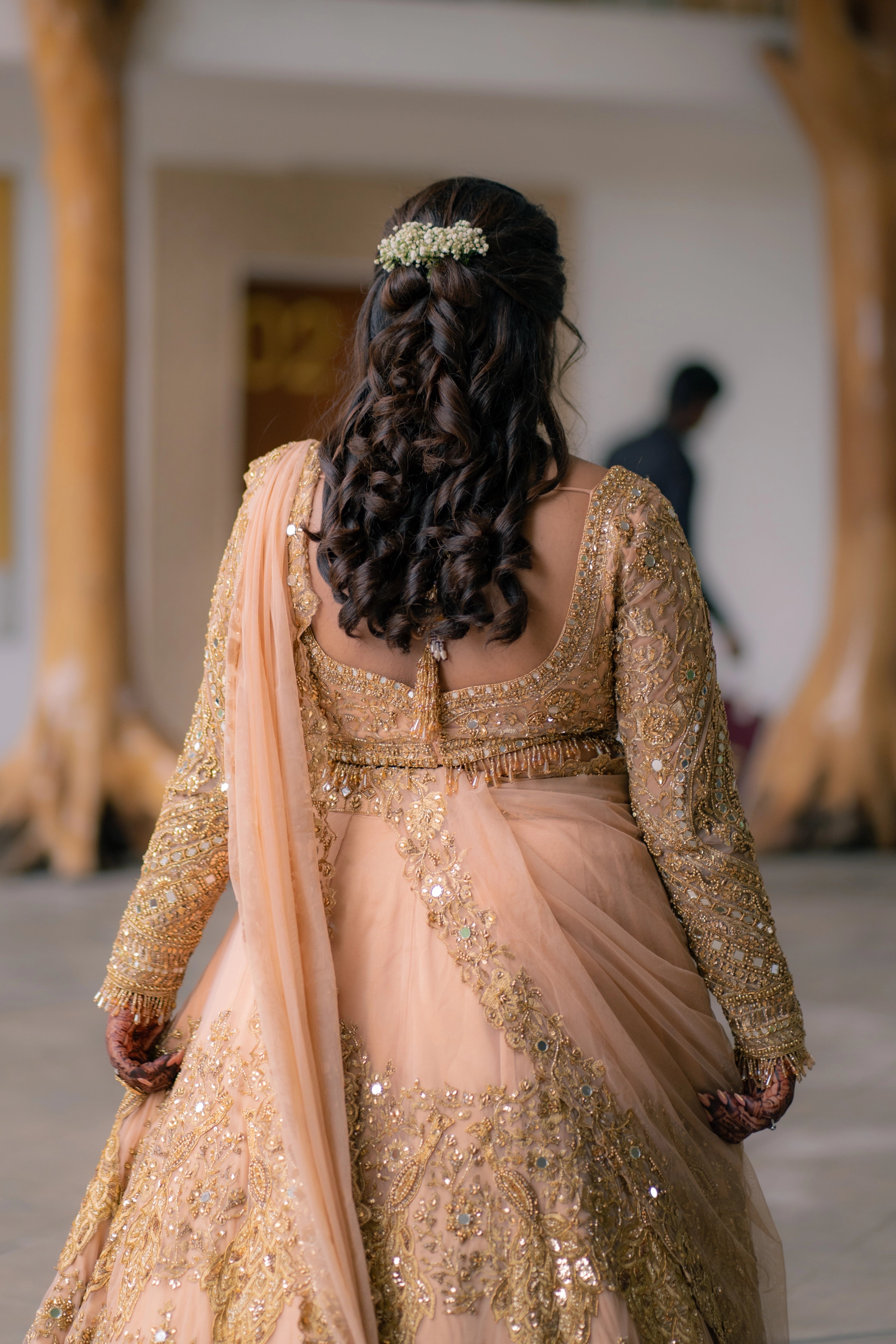Bride Pavithra showcasing back design in a beige gold tulle lehenga, intricately handcrafted with mirrors, sequins, cutdana, beads, crystals and resham by team Archana Karthick.