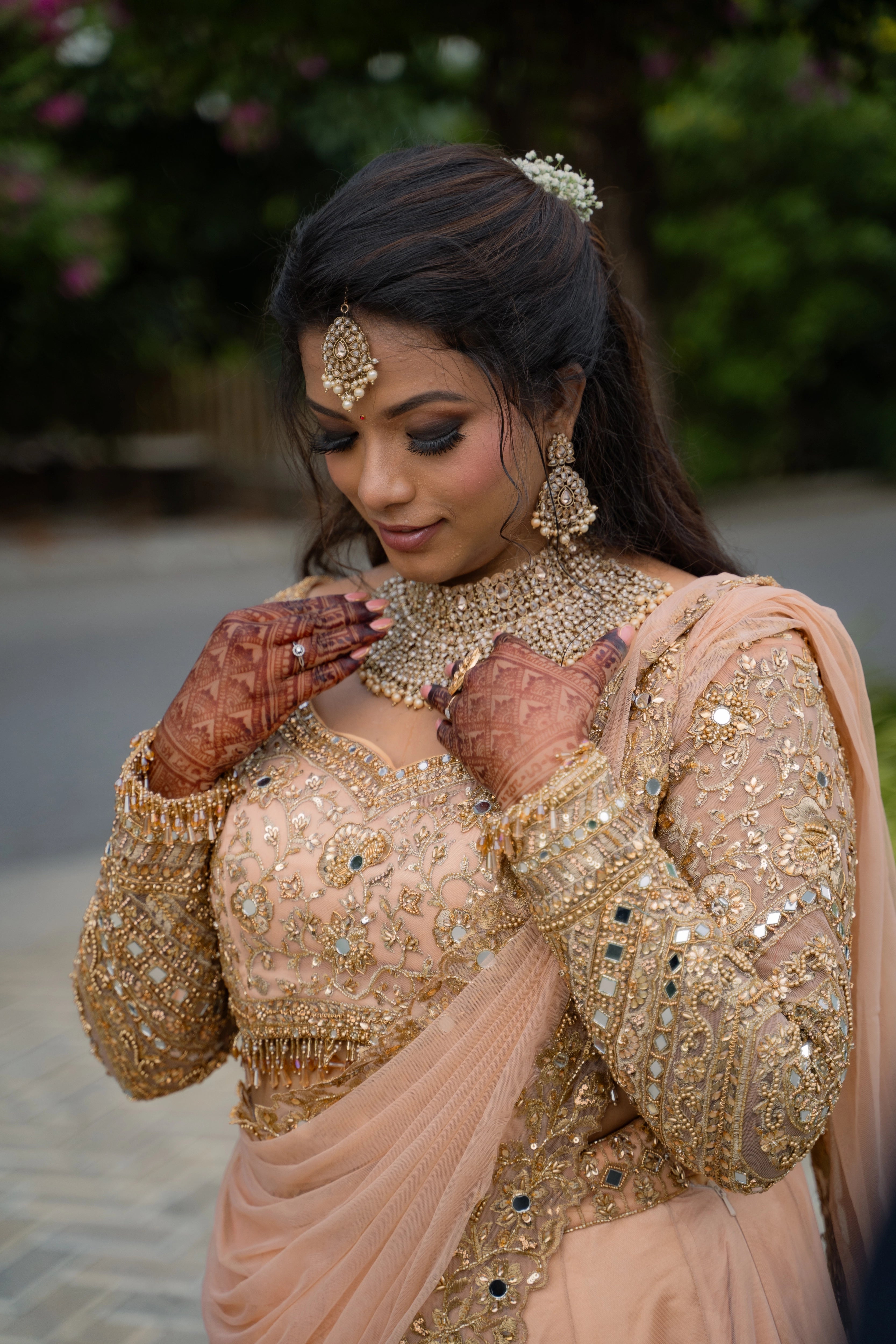 Bride Pavithra showcasing front blouse design in a beige gold tulle lehenga, intricately handcrafted with mirrors, sequins, cutdana, beads, crystals and resham by team Archana Karthick.