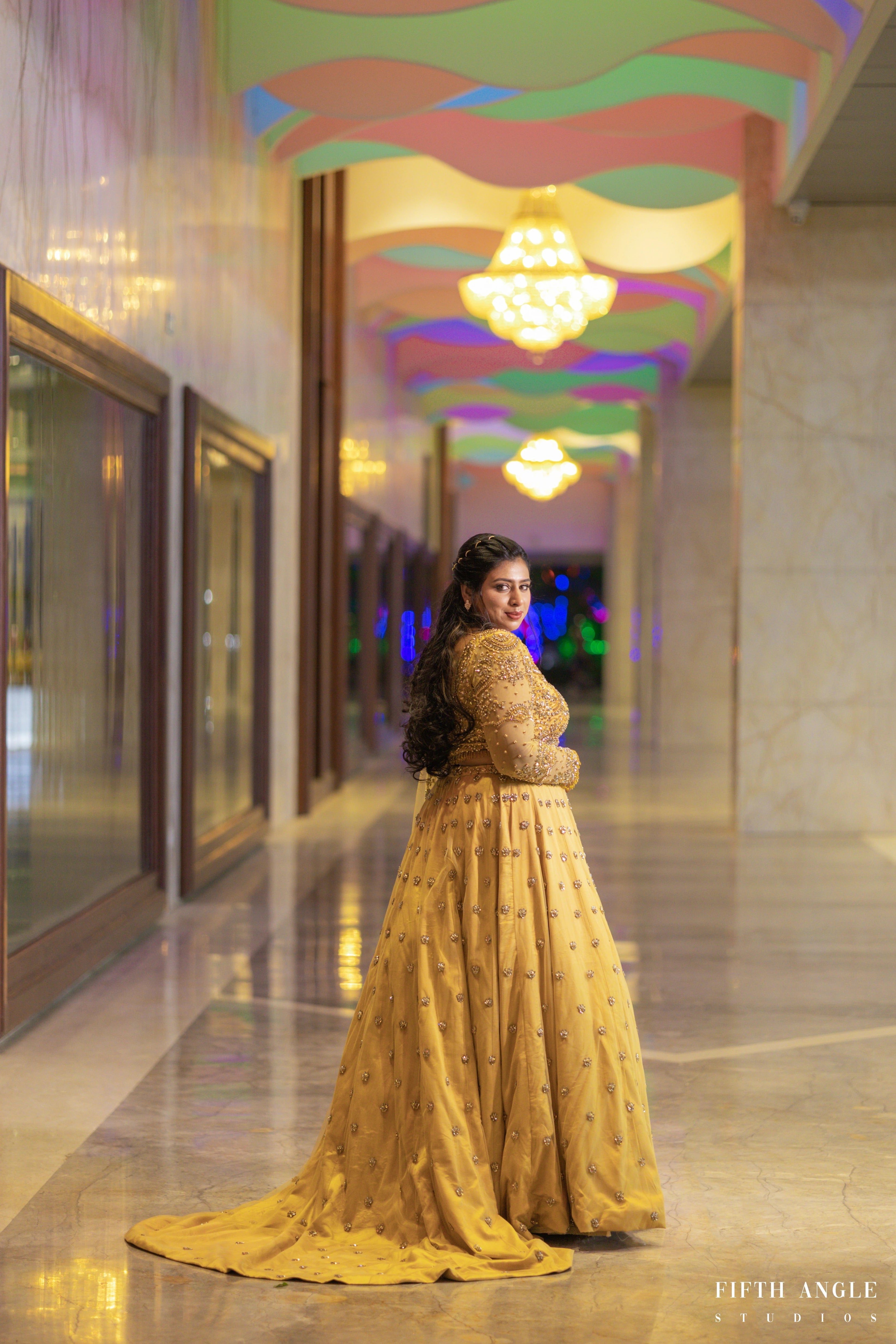 Bride Pooja Das posing in a golden tulle lehenga handcrafted by team Archana Karthick.