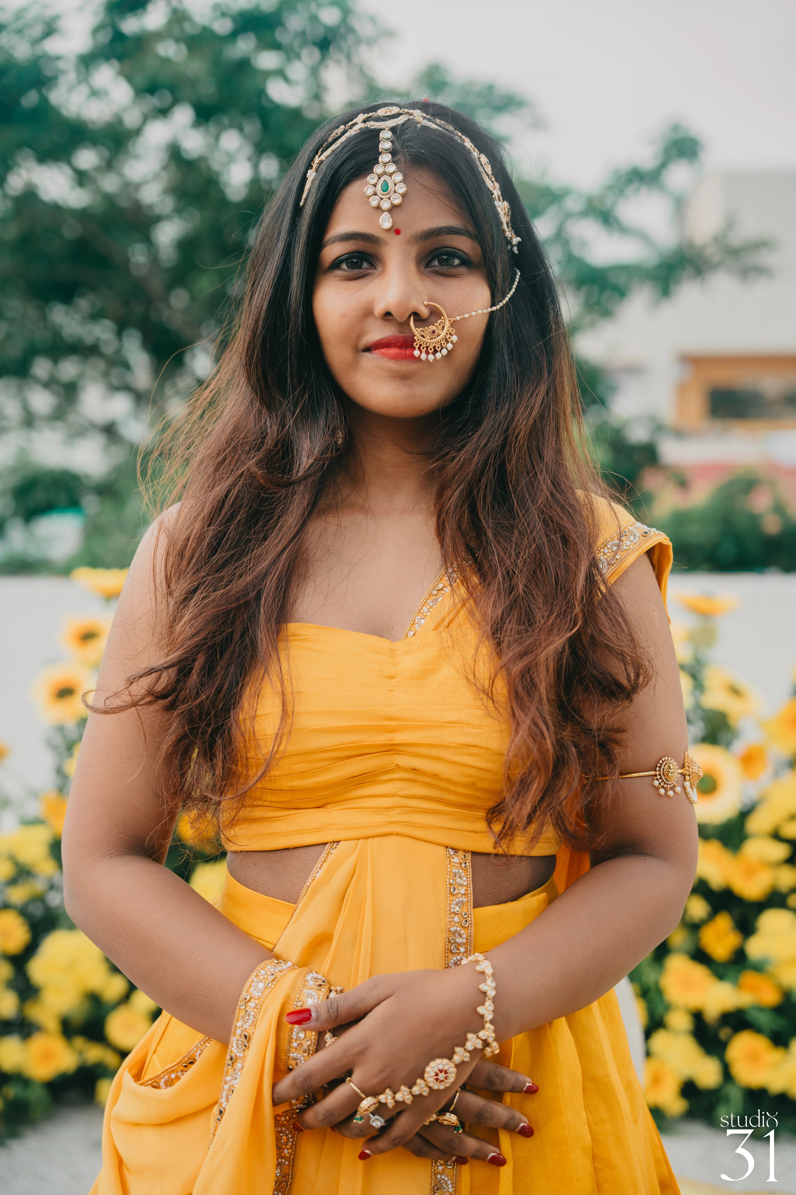 Bride Pooja posing for her haldi in a yellow silk half saree by team Archana Karthick.