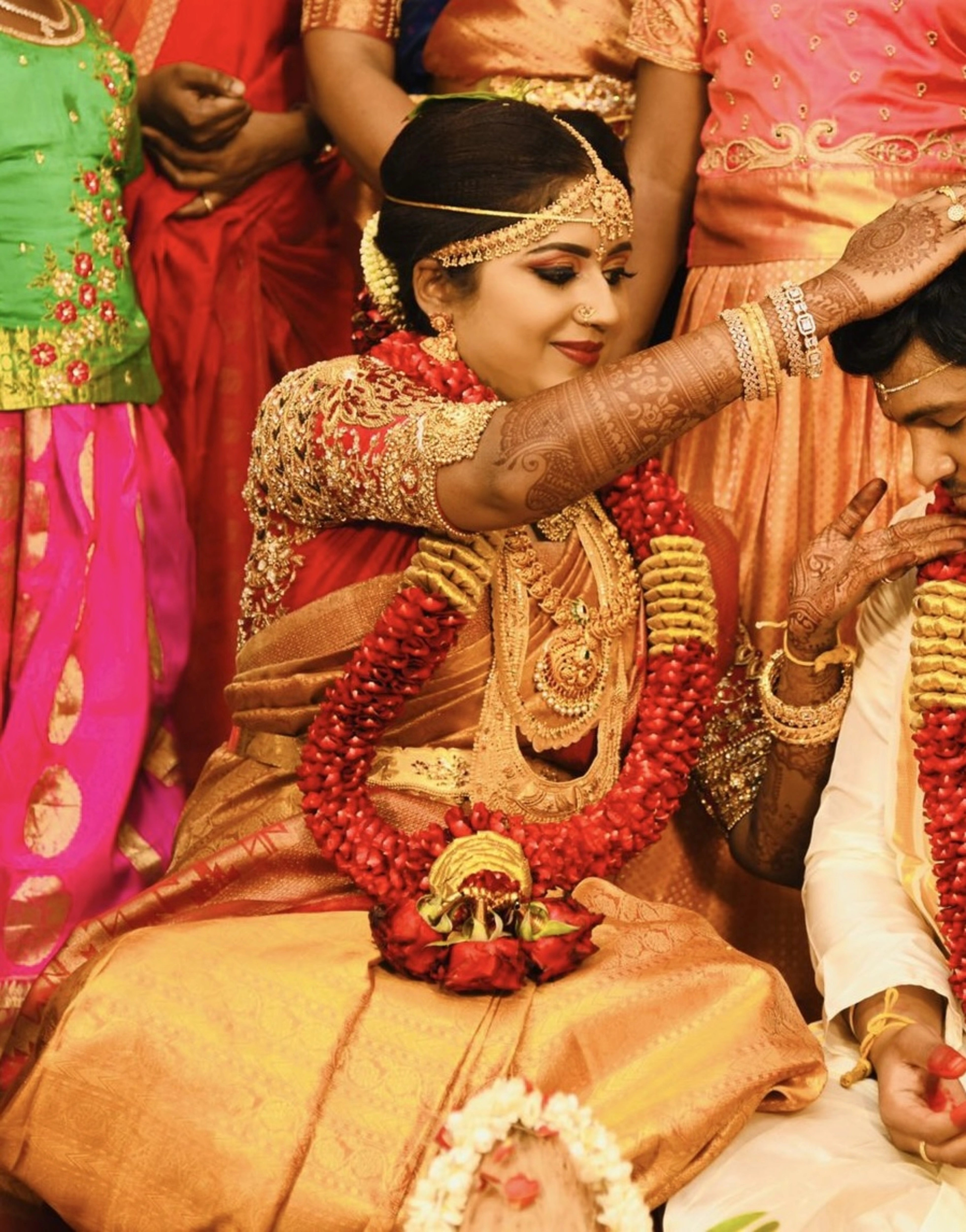 Bride Raji from Ireland during ritual in a red silk blouse, handcrafted with stones, zardozi, beads, sequins and kemp stones and goddess pendant by team Archana Karthick.