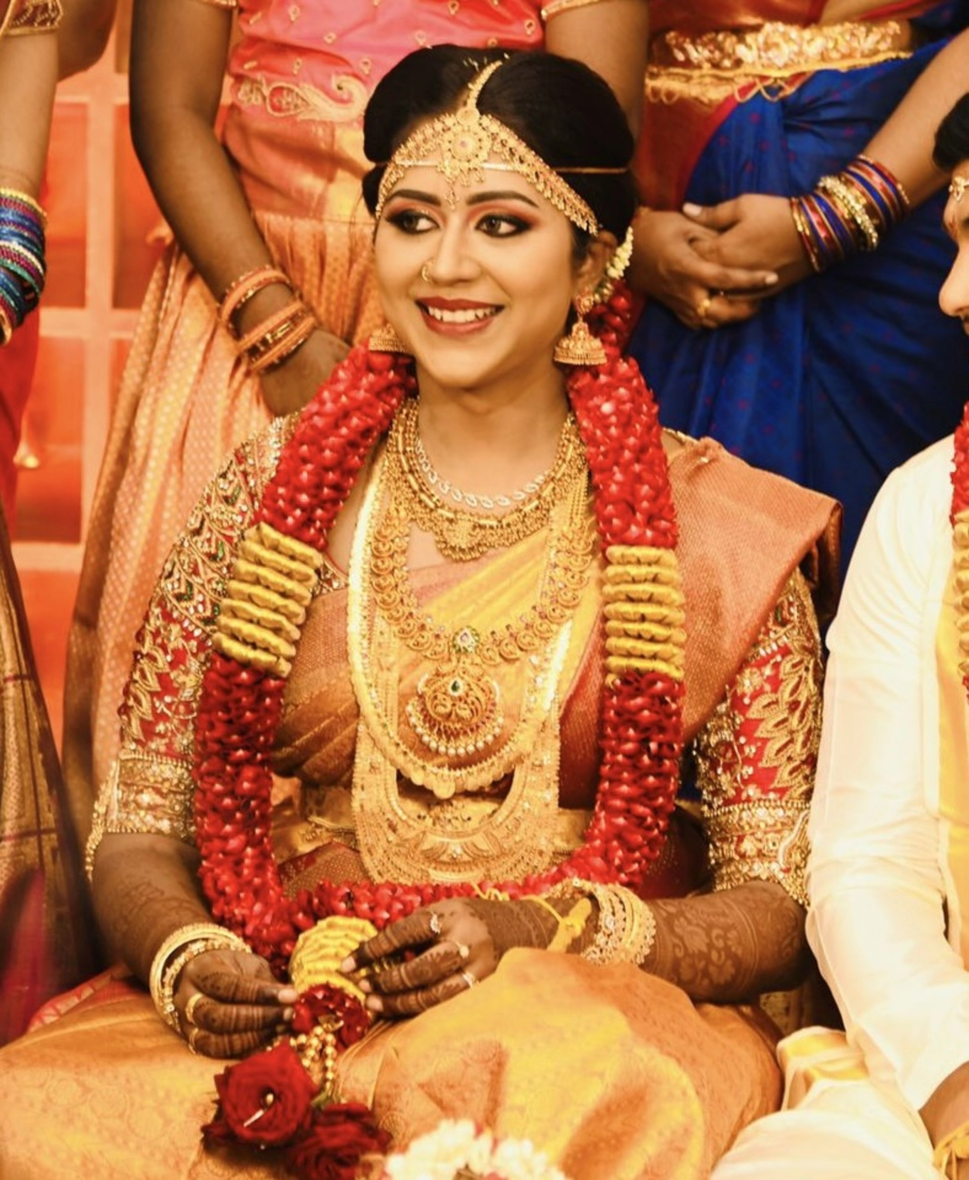 Bride Raji from Ireland posing in a red silk blouse, handcrafted with stones, zardozi, beads, sequins and kemp stones and goddess pendant by team Archana Karthick.