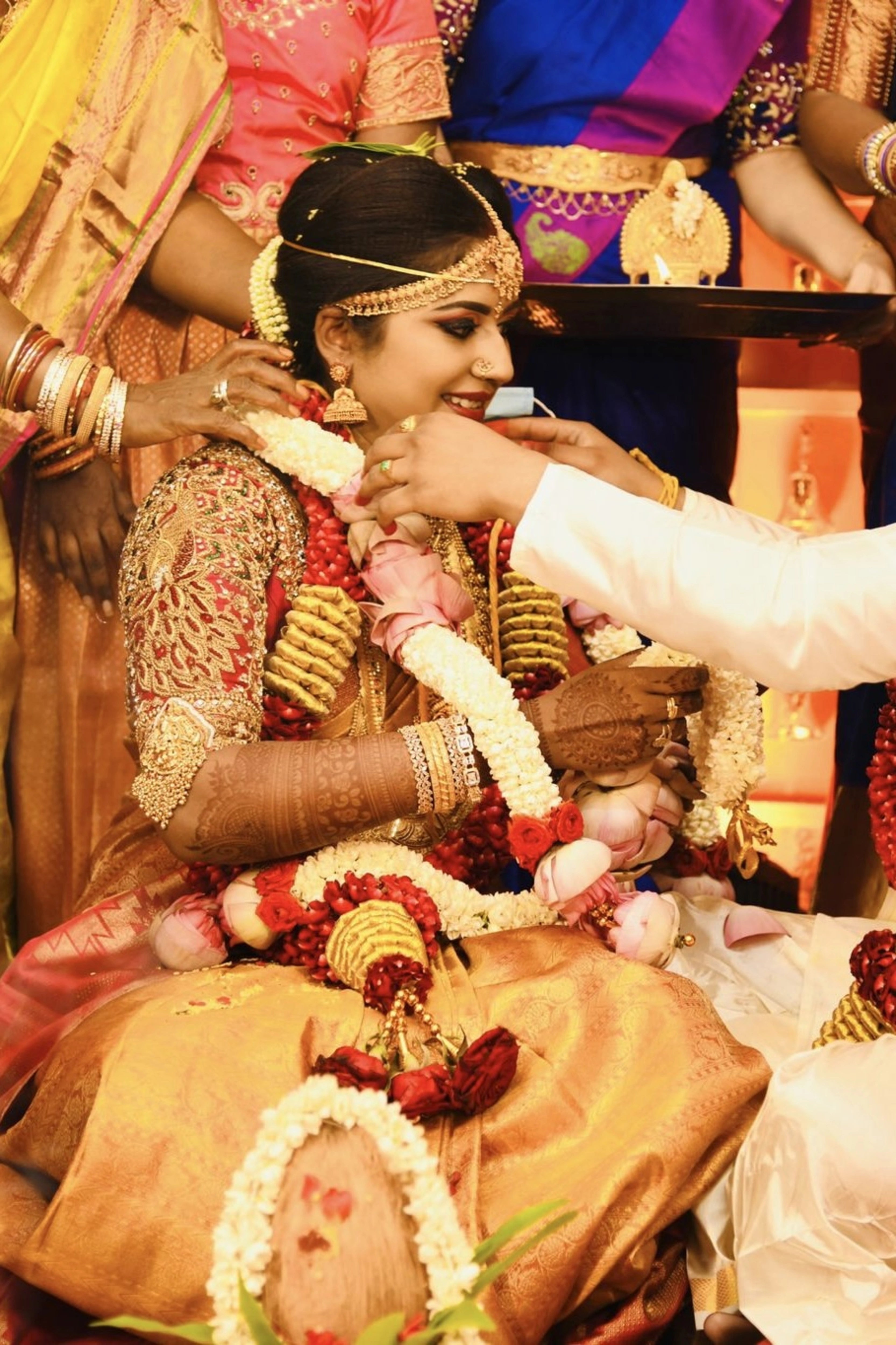 Bride Raji from Ireland smiling in a red silk blouse, handcrafted with stones, zardozi, beads, sequins and kemp stones and goddess pendant by team Archana Karthick.