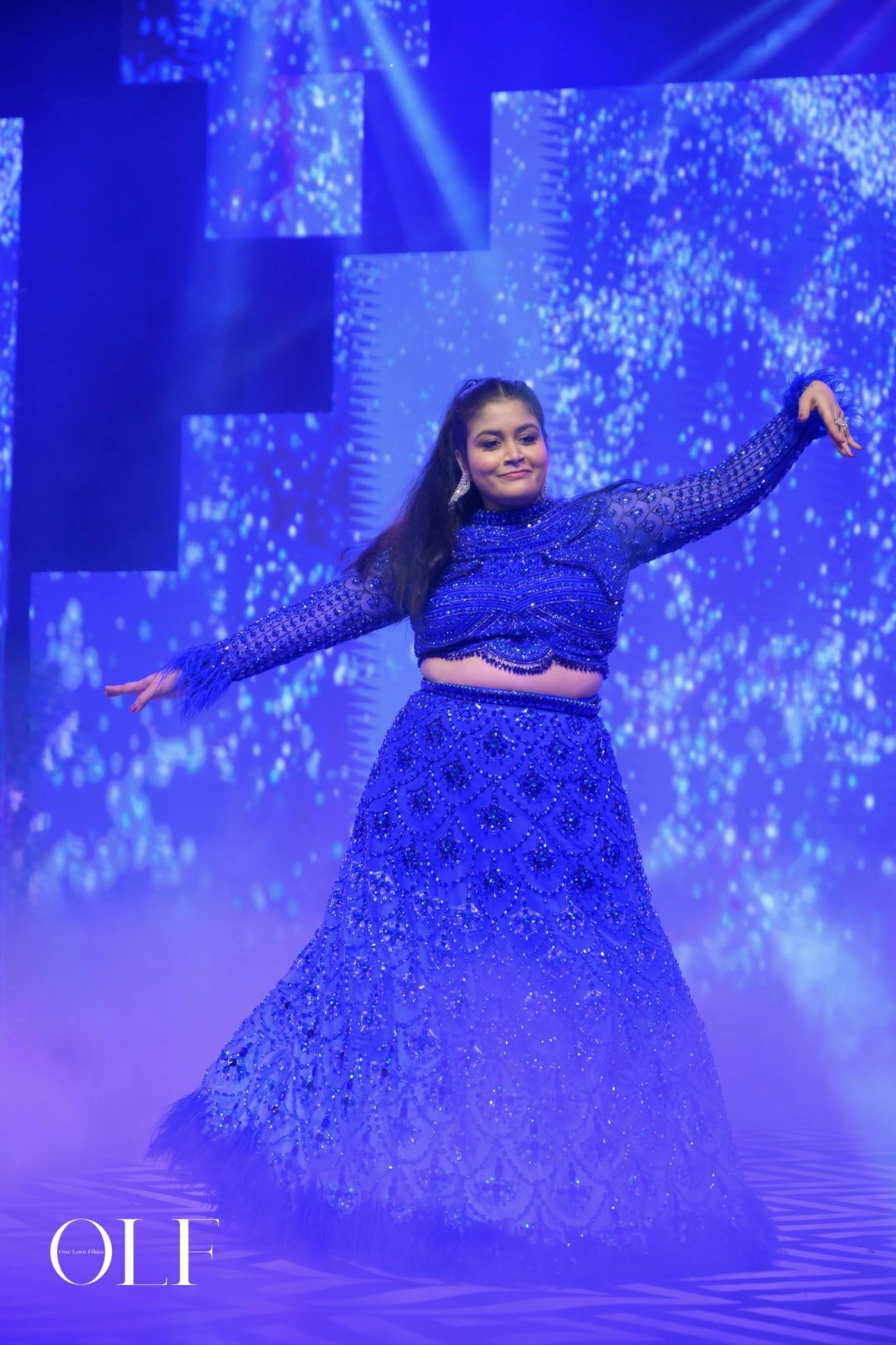 Bride Rasagnya dancing and posing in a peacock themed blue tulle lehenga, handcrafted with rhinestones, crystals, cutdana, sequins and feathers by team Archana Karthick.