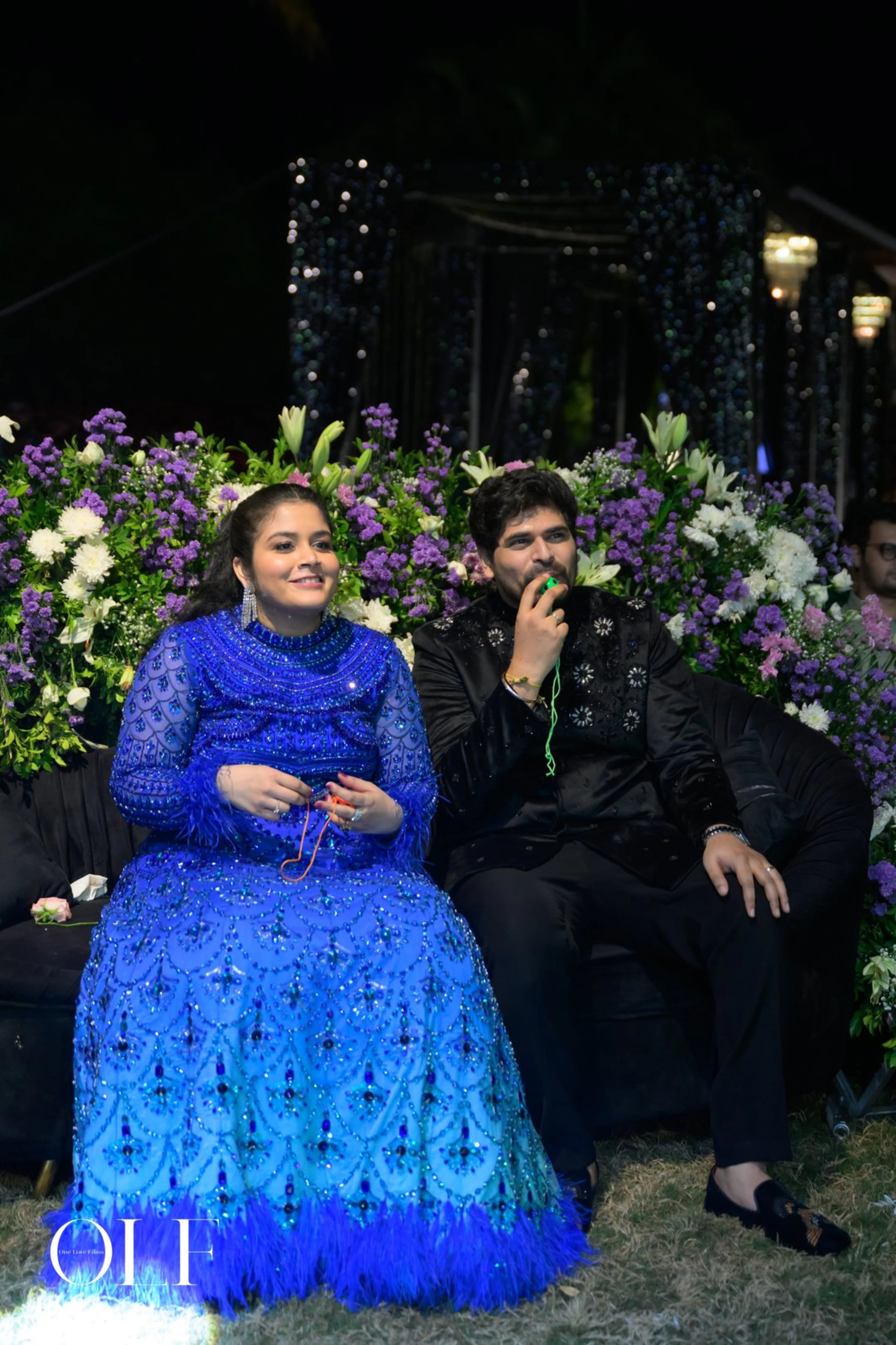 Bride Rasagnya seated with groom in a peacock themed blue tulle lehenga, handcrafted with rhinestones, crystals, cutdana, sequins and feathers by team Archana Karthick.