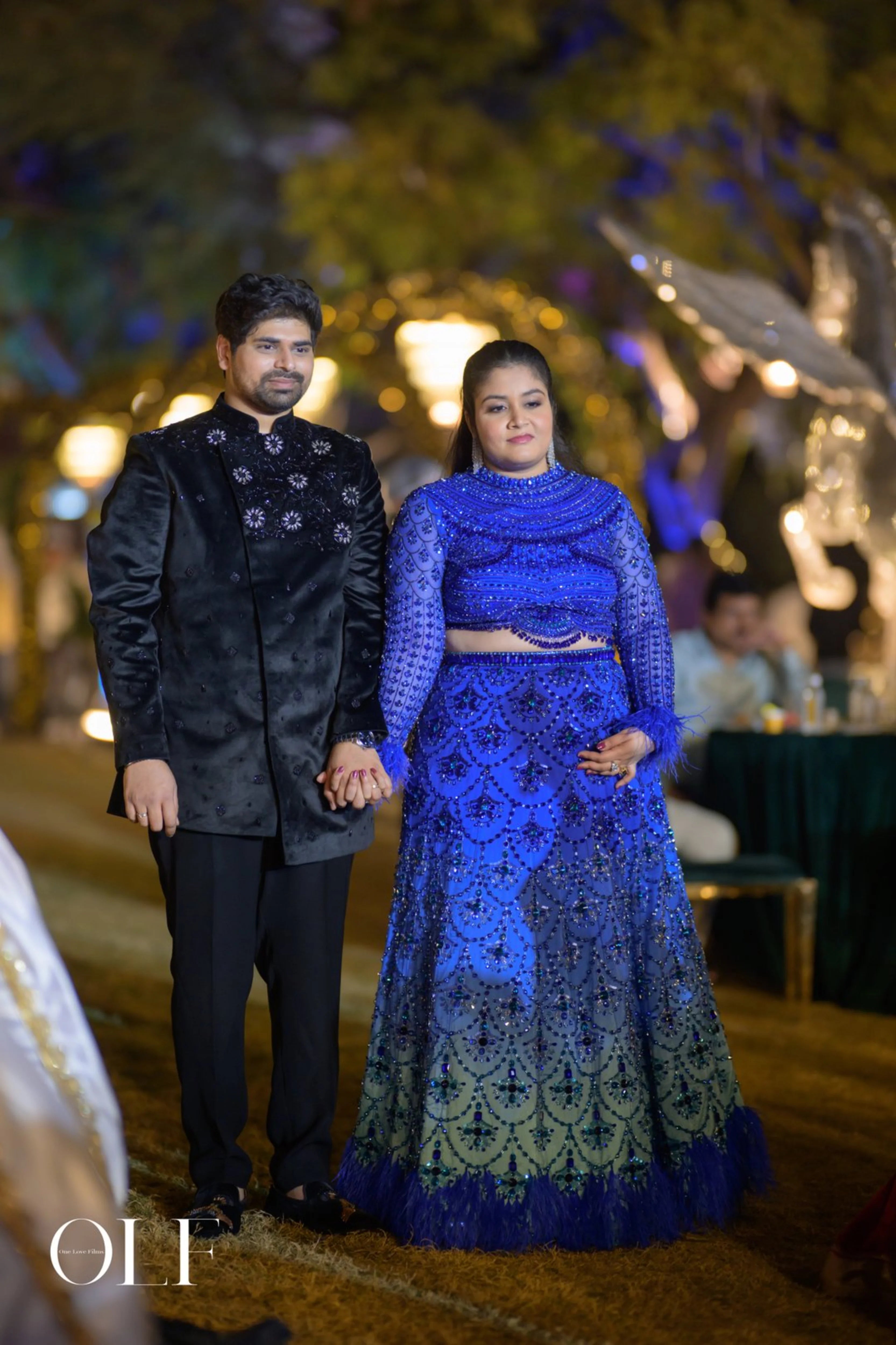 Bride Rasagnya with groom in a peacock themed blue tulle lehenga, handcrafted with rhinestones, crystals, cutdana, sequins and feathers by team Archana Karthick.