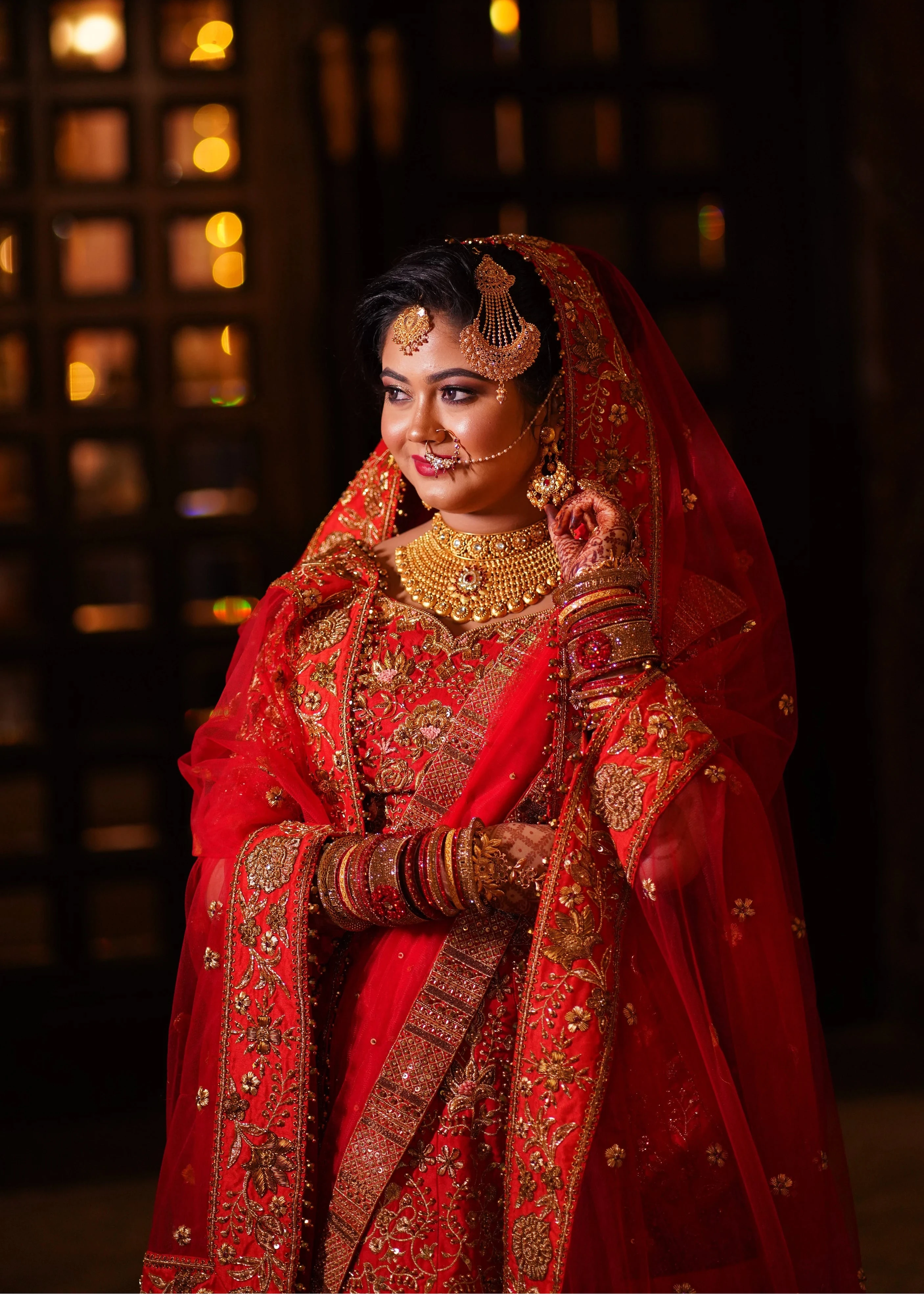 Bride Saba posing in a red raw silk lehenga with a veil and dupatta handcrafted by team Archana Karthick.