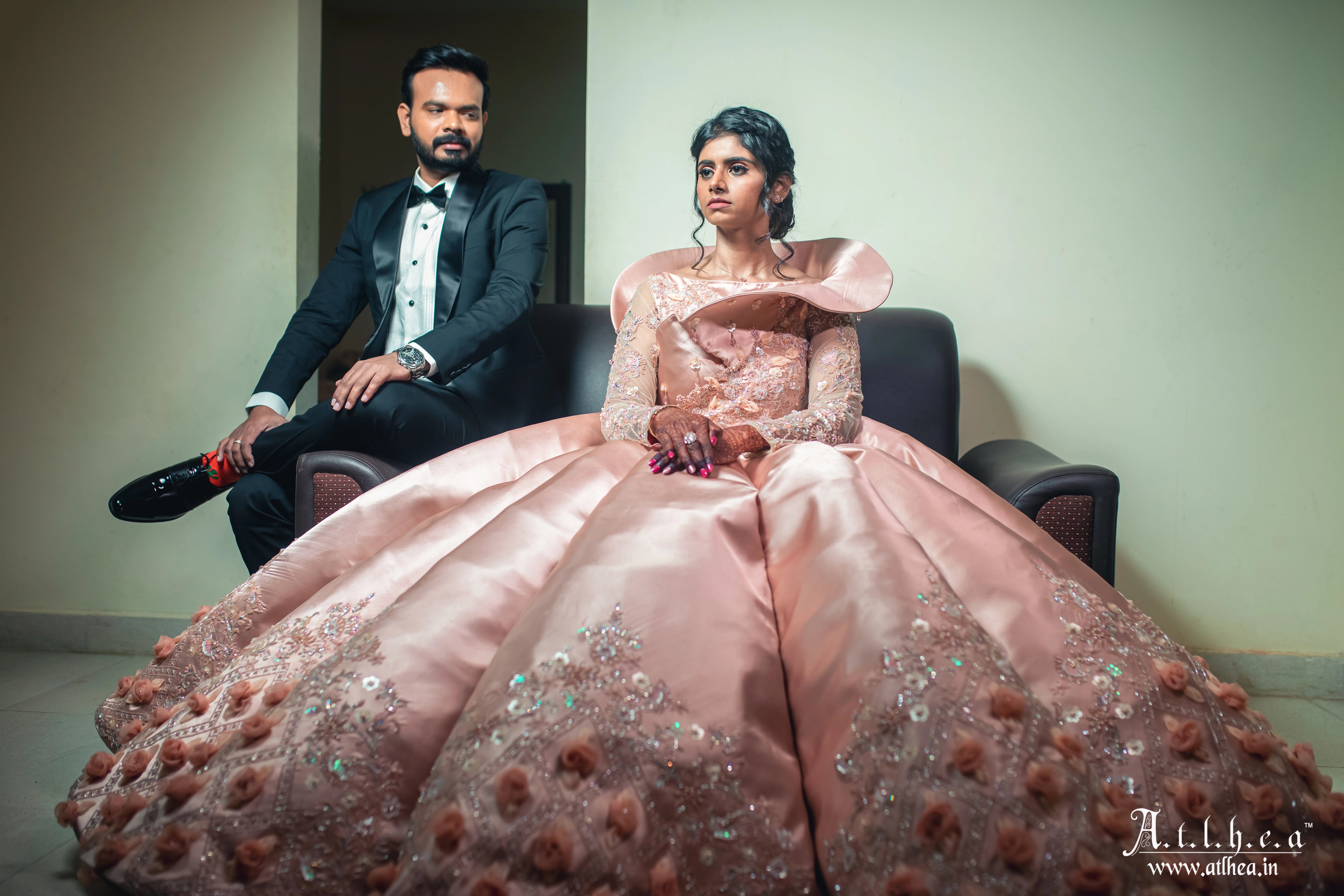 Bride Sahana posing with groom in a peach cream satin structured ball gown, handcrafted intricately with applique, sequins, stones and cutdana by team Archana Karthick.