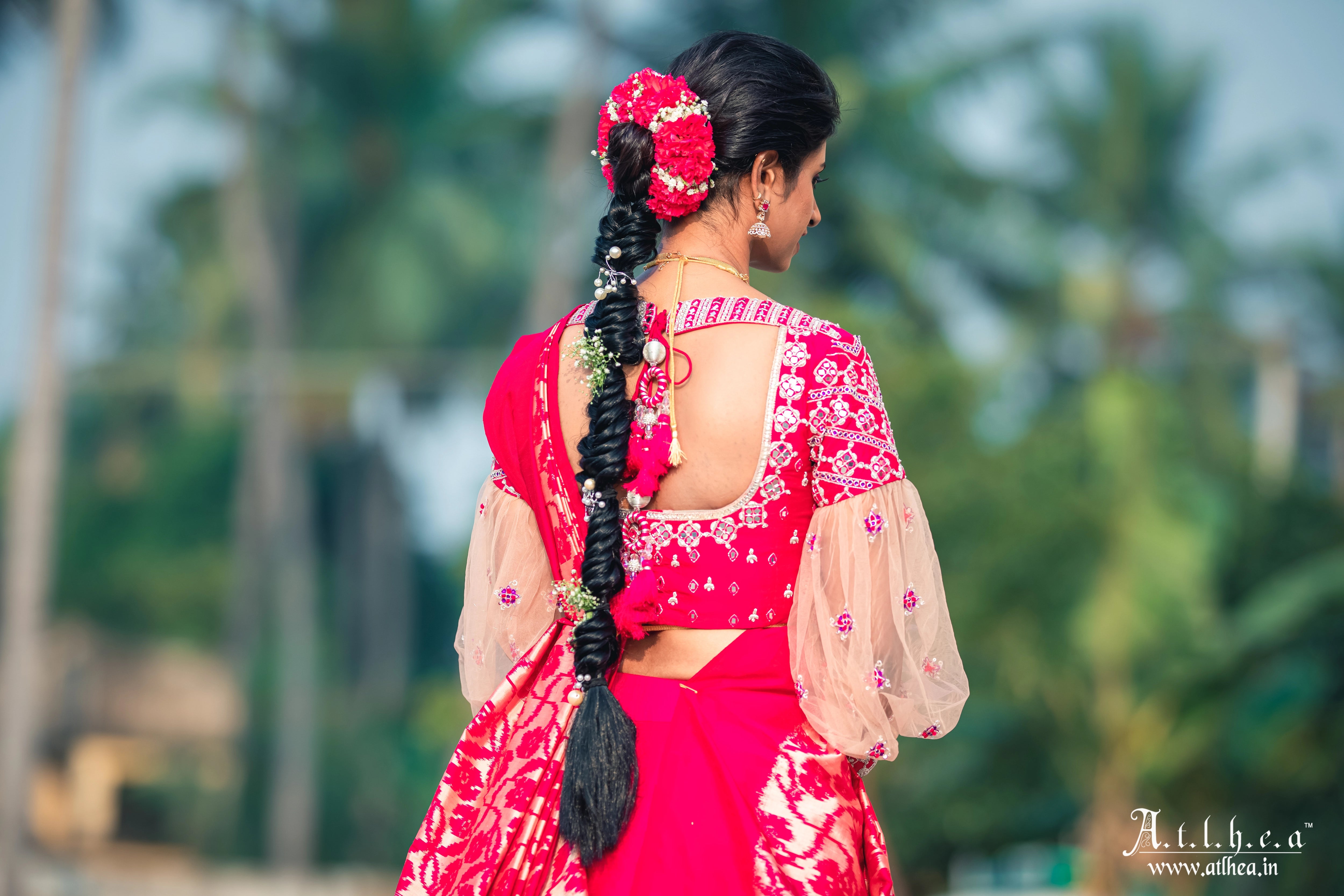 Bride Sahana showcasing back blouse design in a raspberry raw silk half saree, handcrafted intricately with mirror, stones, zardozi and resham by team Archana Karthick.