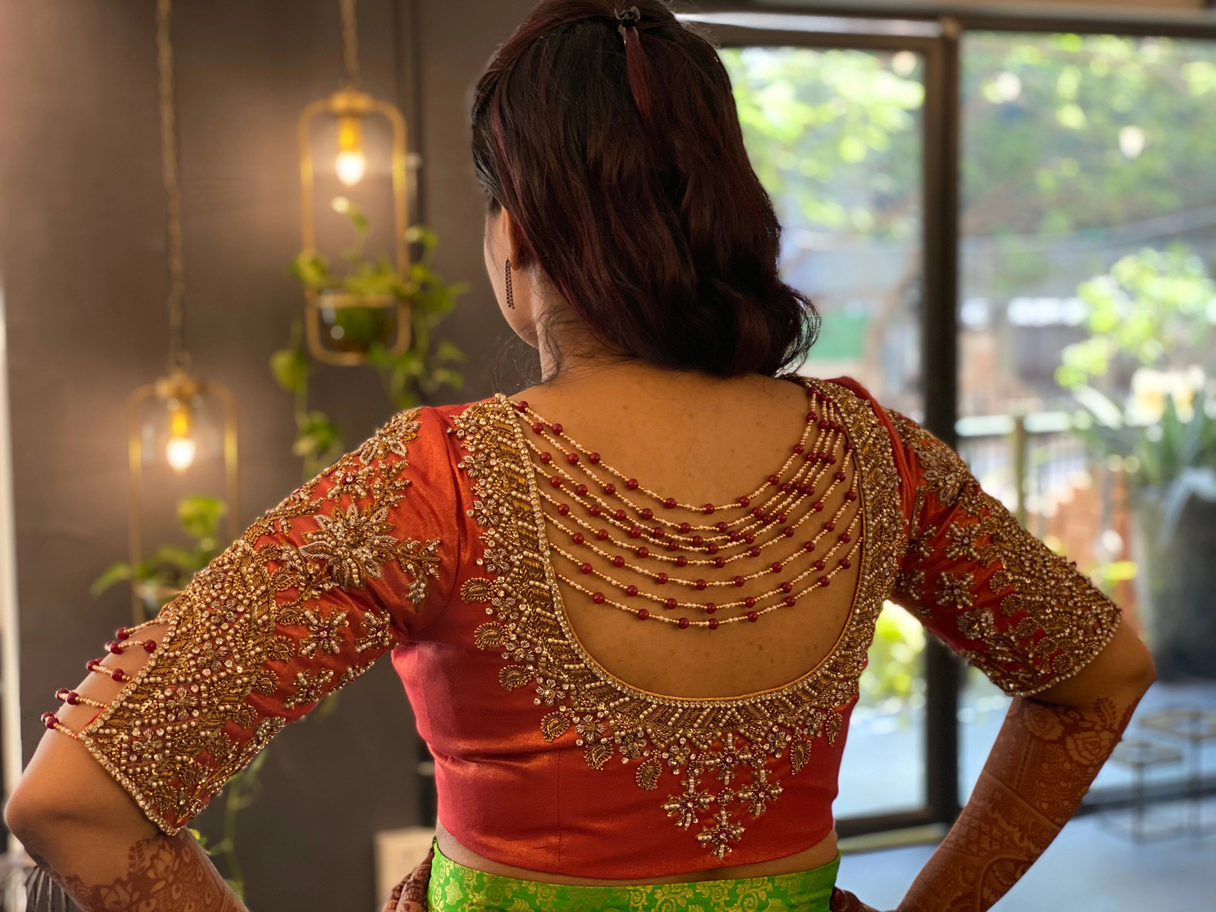 Bride Sai Sridevi posing in a burnt orange silk blouse handcrafted by team Archana Karthick.