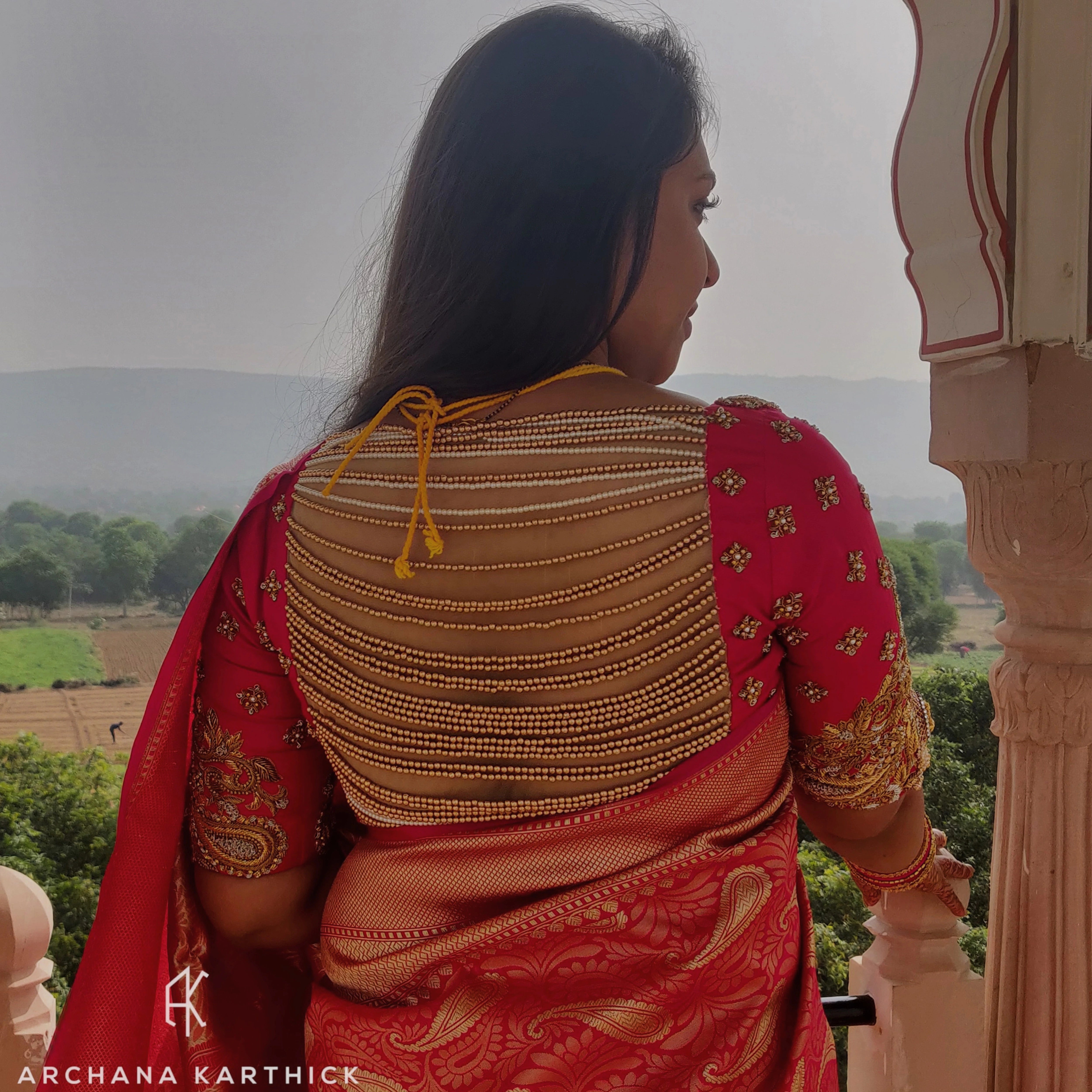 Bride Sanjana posing in a pink silk blouse handcrafted by team Archana Karthick.