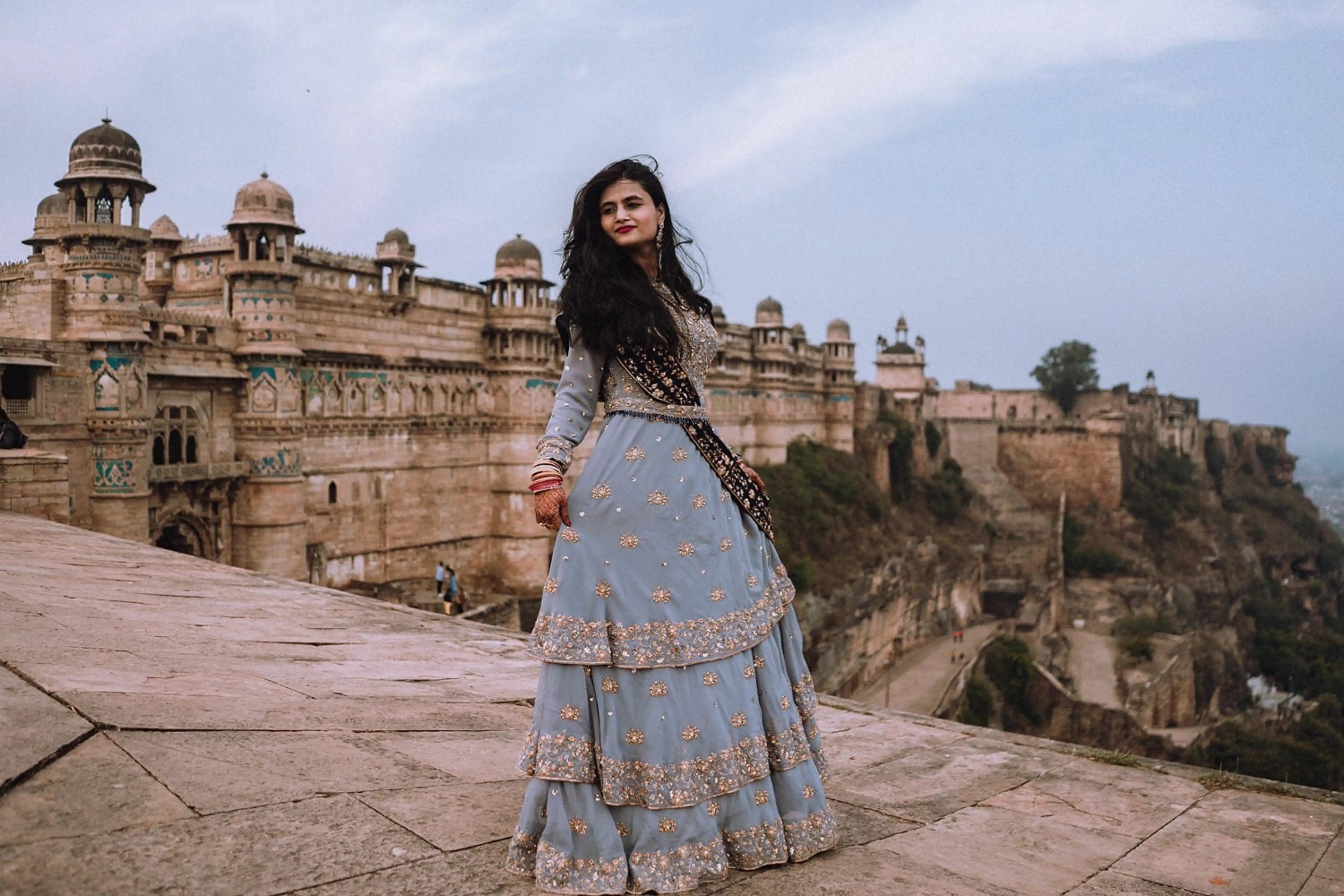Bride Sapna Tapadia from Australia striking a pose in a layered gown in aqua grey georgette, paired with a navy blue dupatta. Intricately handcrafted by team Archana Karthick.