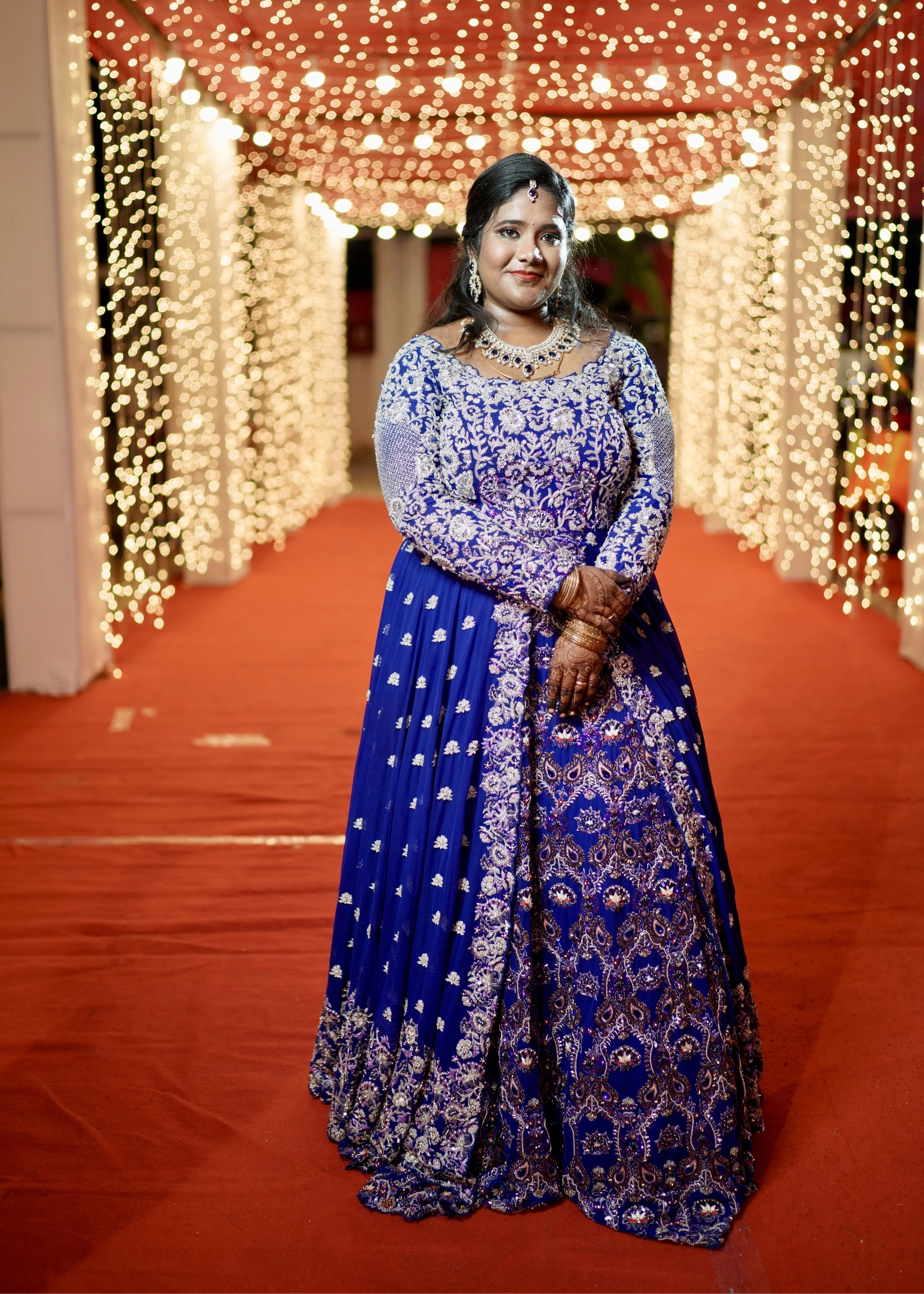 Bride Sathiyapriya in a midnight blue georgette masakali lehenga for her reception in Dindigul, looking straight at camera