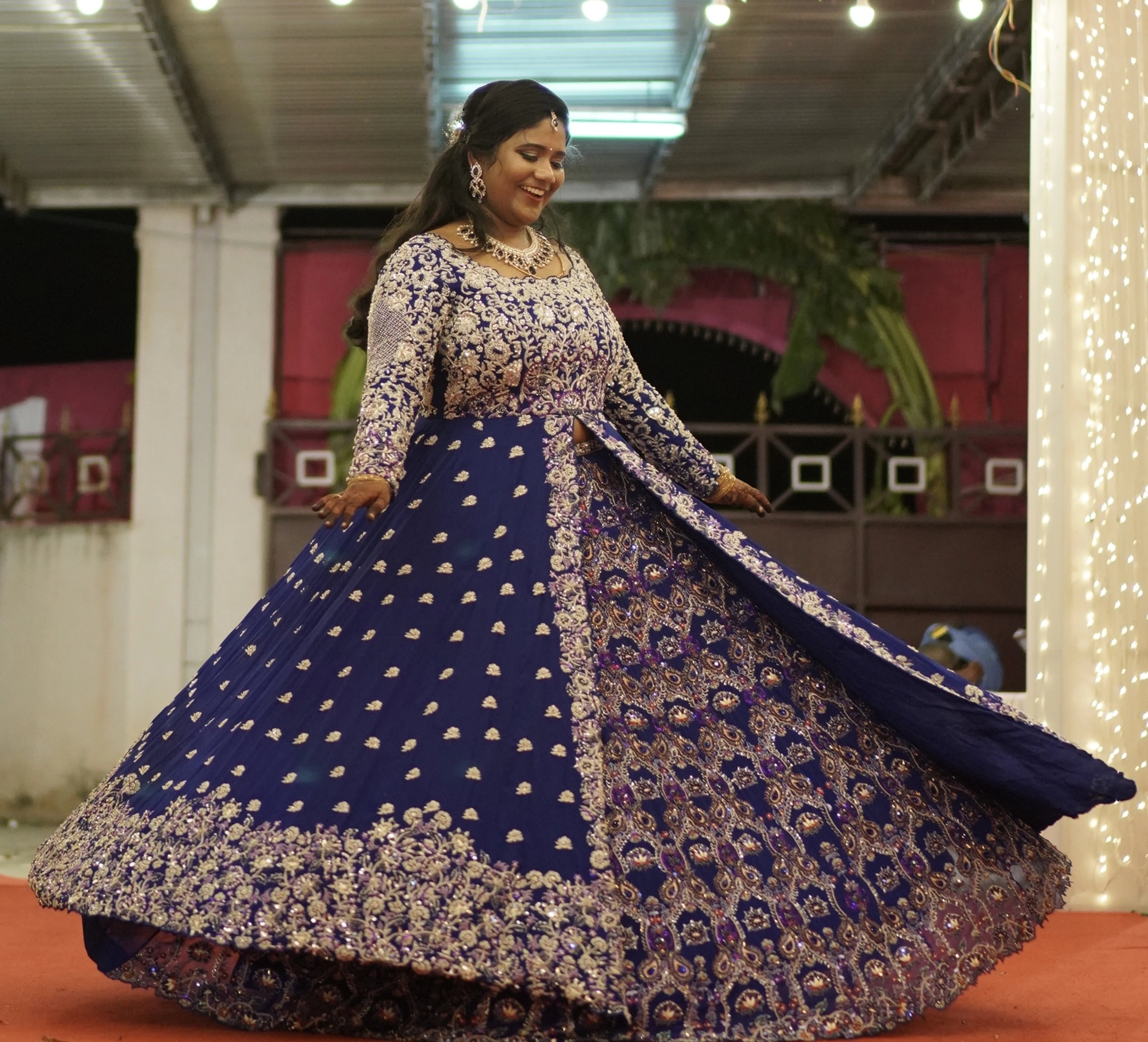 Bride Sathiyapriya twirling and looking down in a midnight blue georgette masakali lehenga for her reception in Dindigul