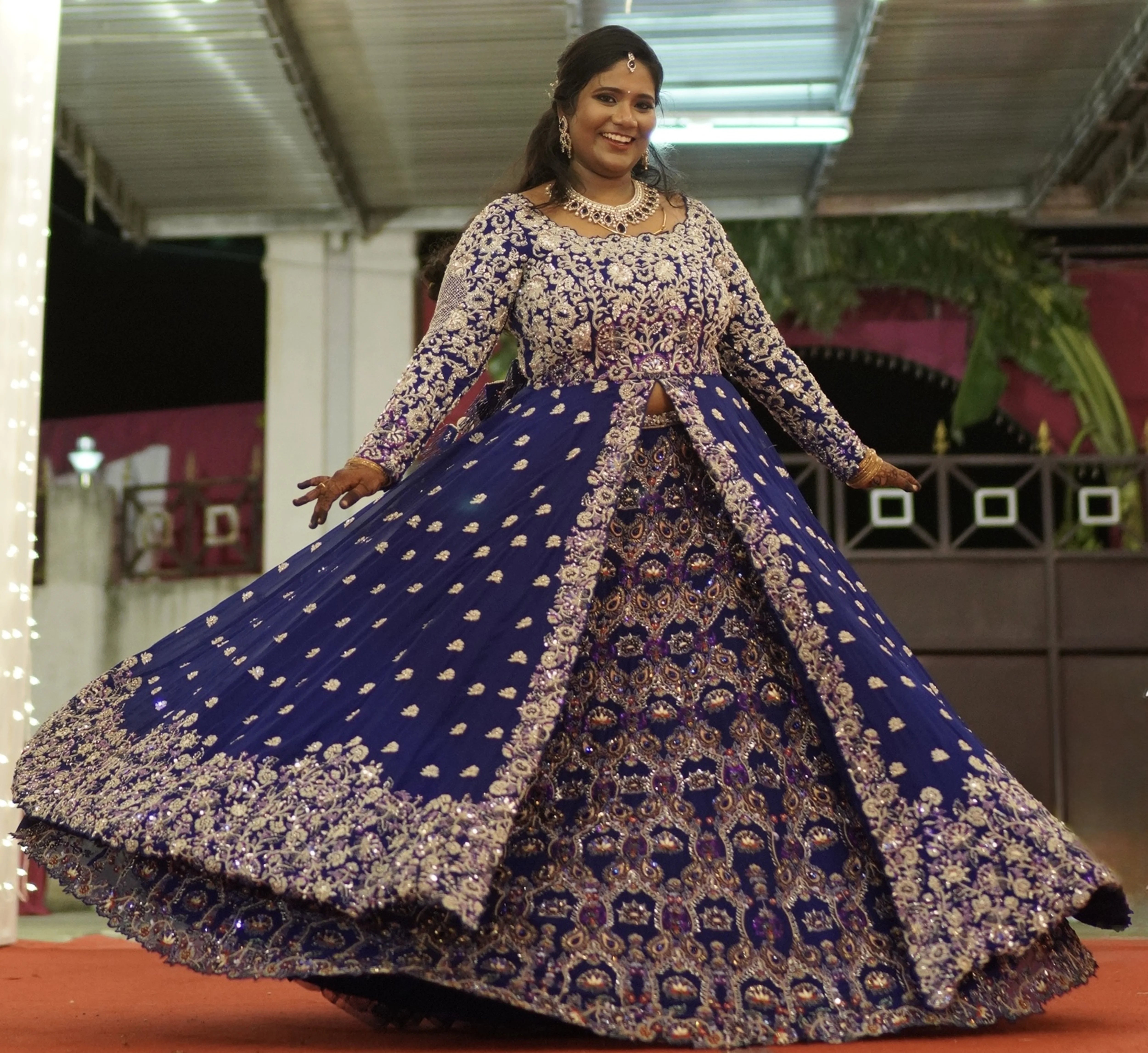 Bride Sathiyapriya twirling and smiling in a midnight blue georgette masakali lehenga for her reception in Dindigul