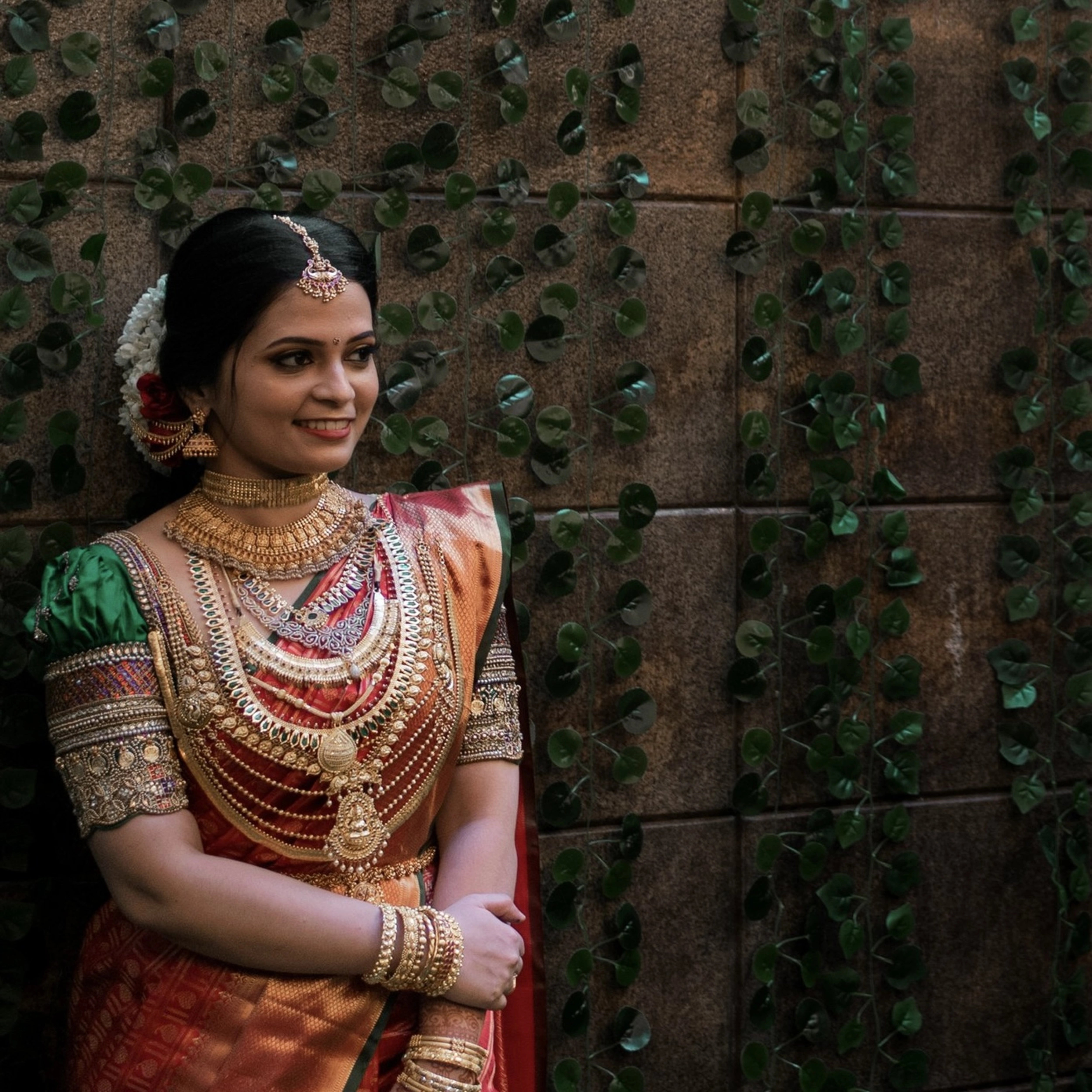 Bride Shalini from Kerala posing in a handcrafted green silk blouse embellished with beads, zardozi, kundan, kemp stones, coins & pearls by team Archana Karthick.