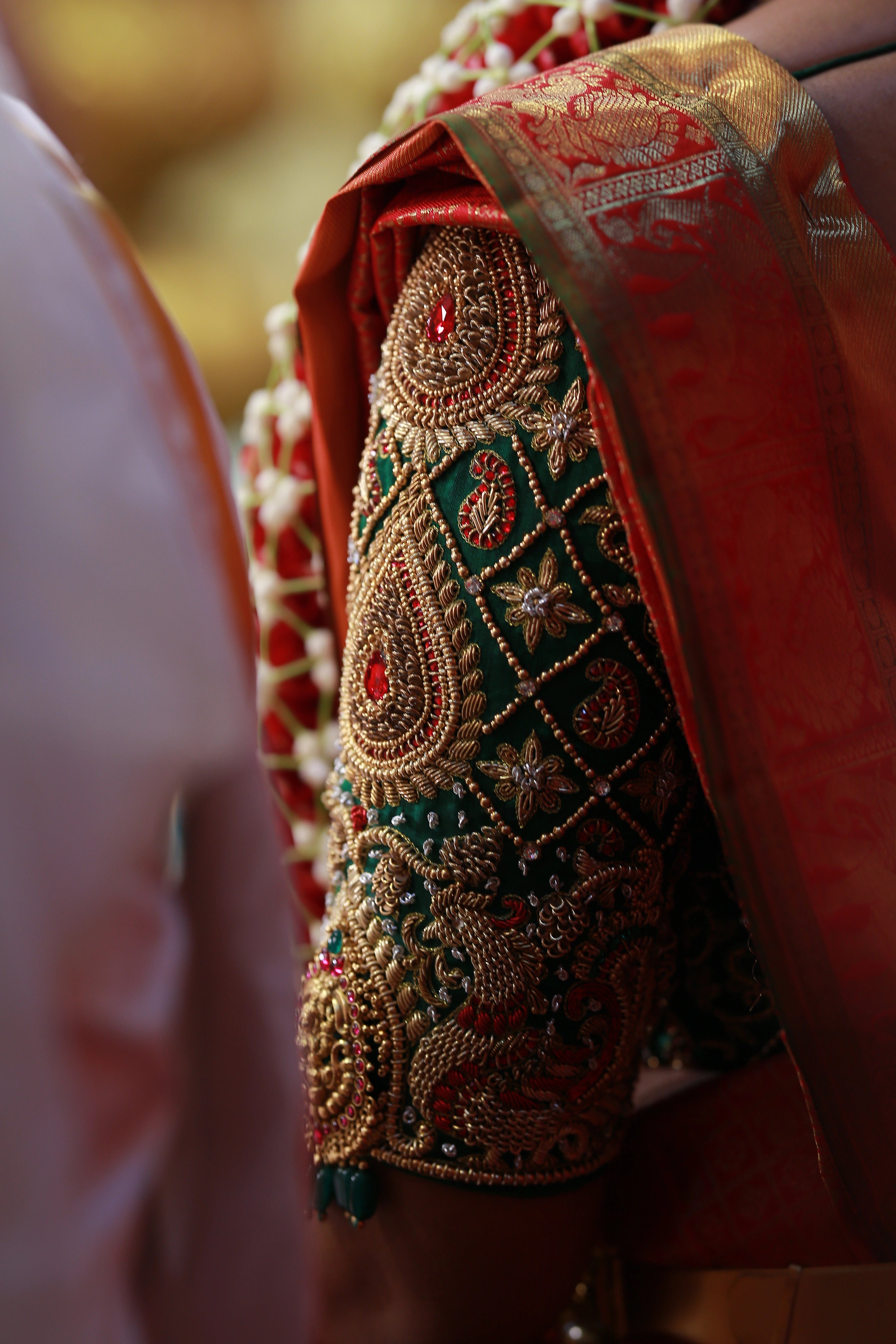 Bride Shanmuga Priya showcasing blouse sleeve in a bottle green silk blouse for her wedding, handcrafted with beads, zardozi, kundan and crystals by team Archana Karthick.