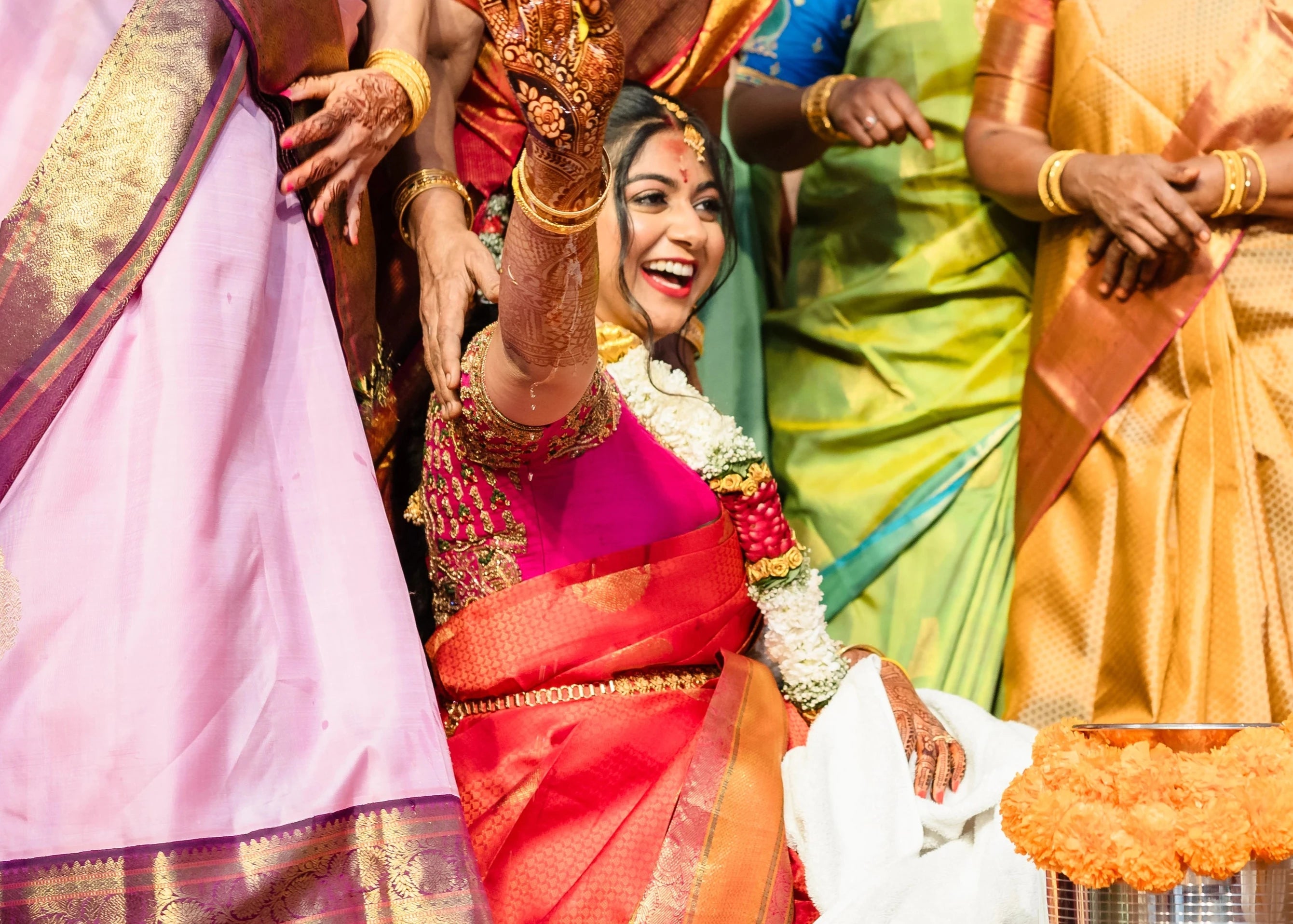 Bride Shivani laughing in a magenta silk blouse, intricately handcrafted with beads, stones, resham, mirrors, jhumkas and zardozi by team Archana Karthick.